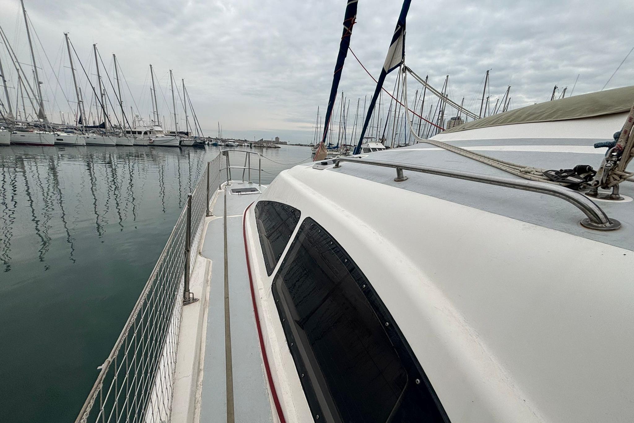 1998 Prout 38 catamaran docked in a marina, surrounded by sailboats under cloudy skies.