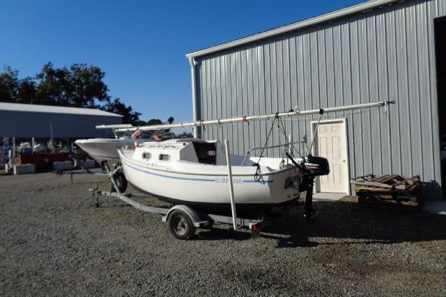 2007 Sanibel 18 Pocket Cruiser sailboat on trailer near metal building.