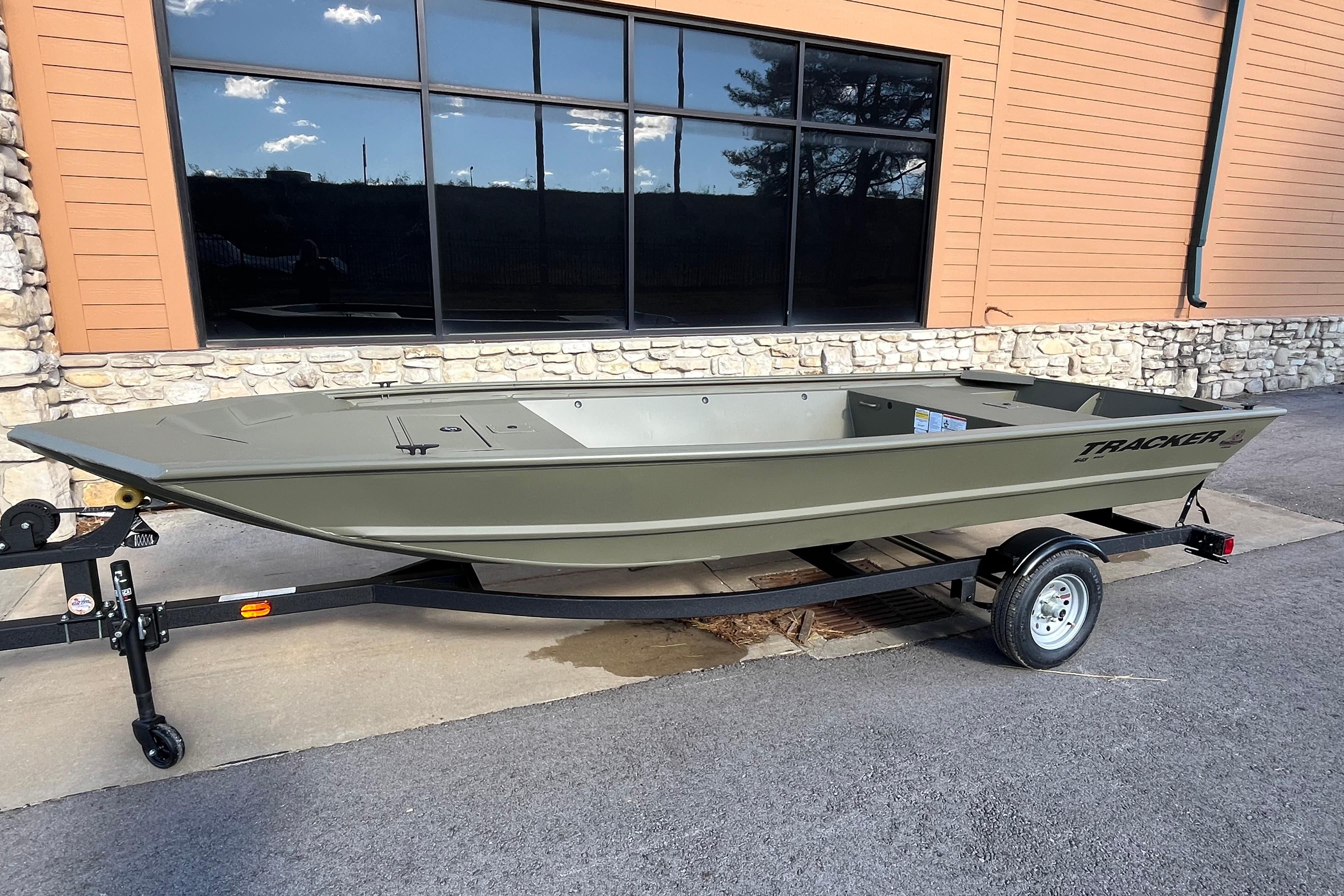 2026 Tracker Grizzly 1648 Utility boat on trailer, parked outside a building.