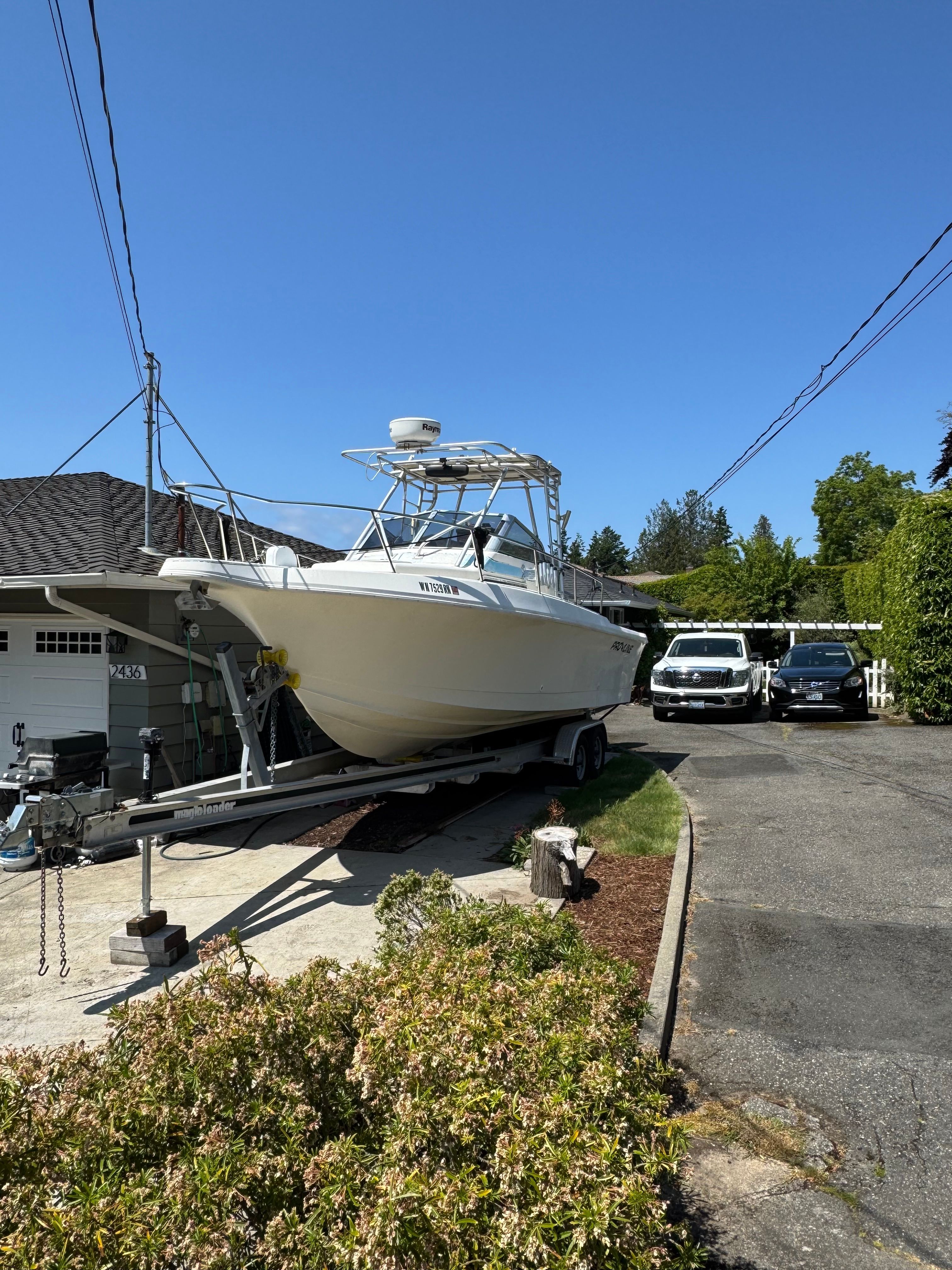 A 1991 Pro-Line Walkaround boat is on a trailer in a driveway.