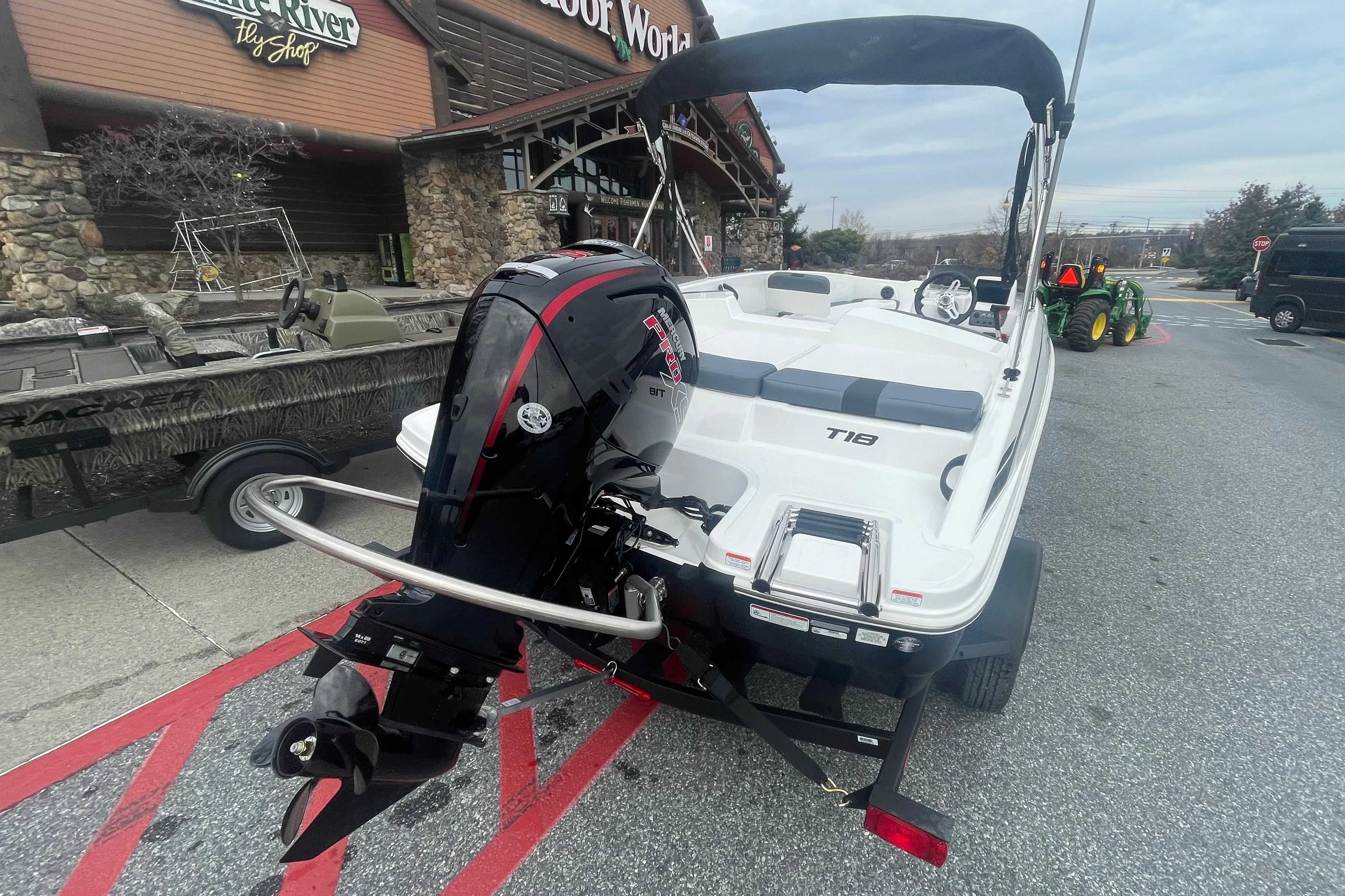 2026 Tahoe T18 boat with outboard motor parked outside a store.