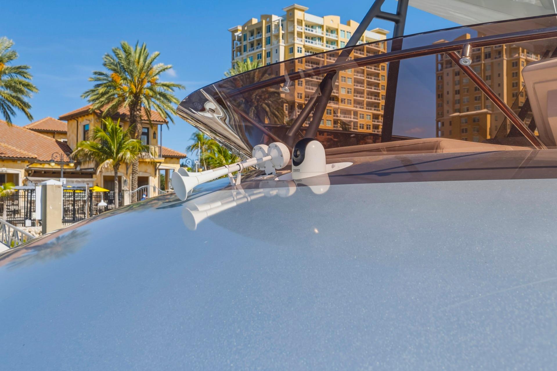 2022 Prestige 520 yacht with sleek design, docked near palm trees and luxury buildings.
