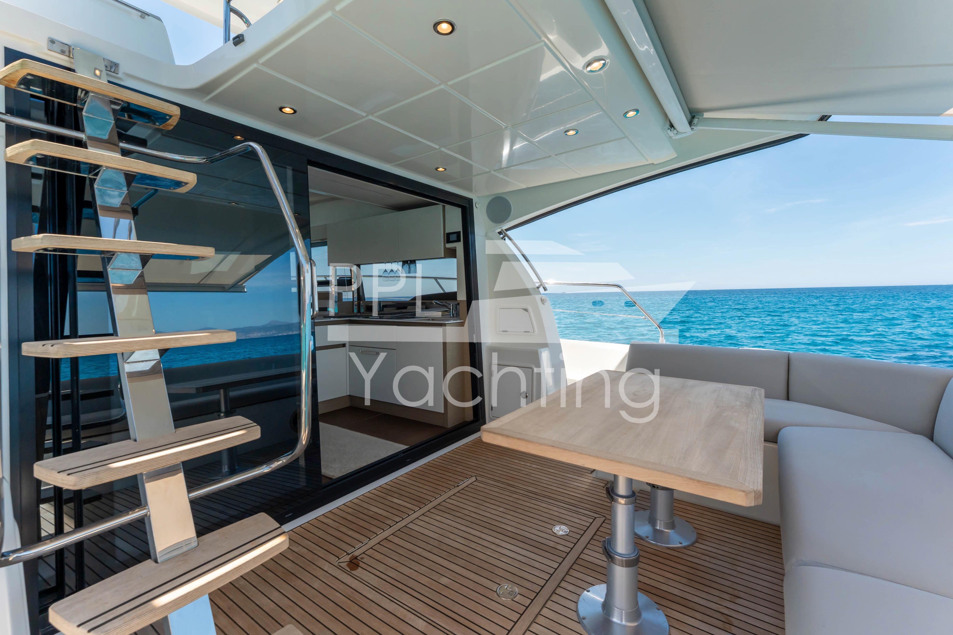 Luxurious 2019 Prestige 460 yacht interior with ocean view, featuring modern seating and staircase.