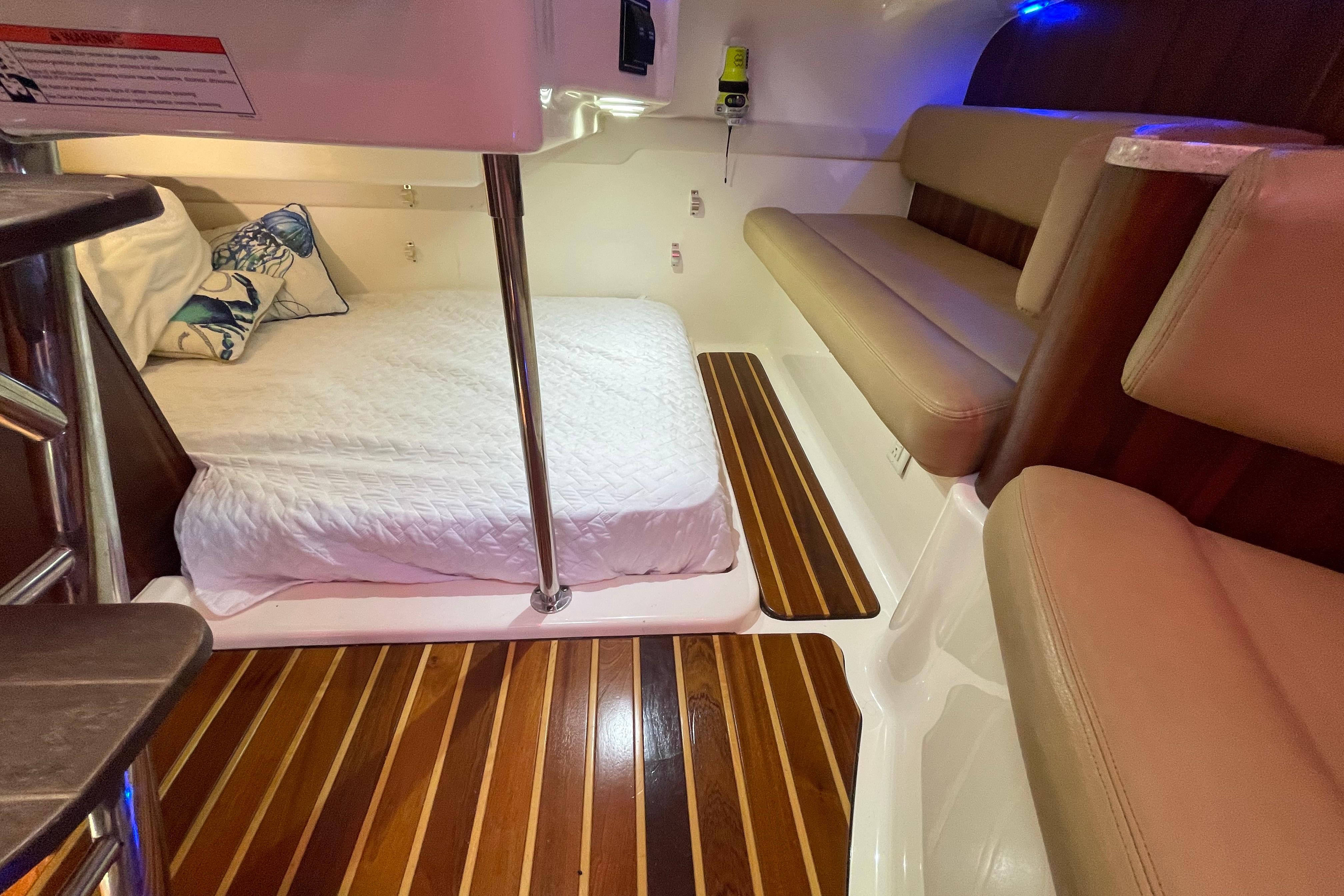 2010 Pursuit OS 375 Offshore cabin with bed, seating, and wooden flooring.