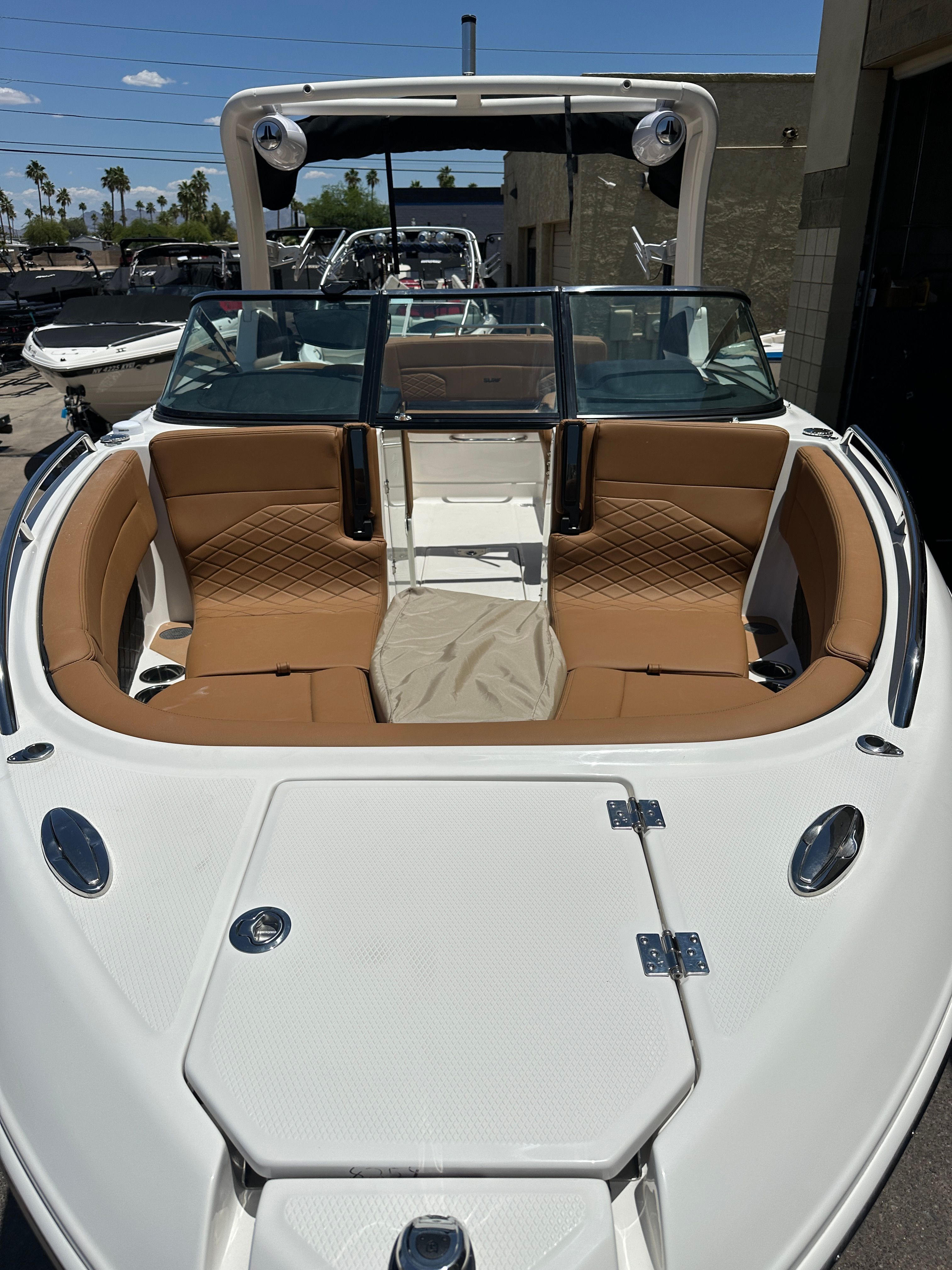 Chaparral 26 Surf 2025: Spacious bow area with brown upholstery and glass windshield.