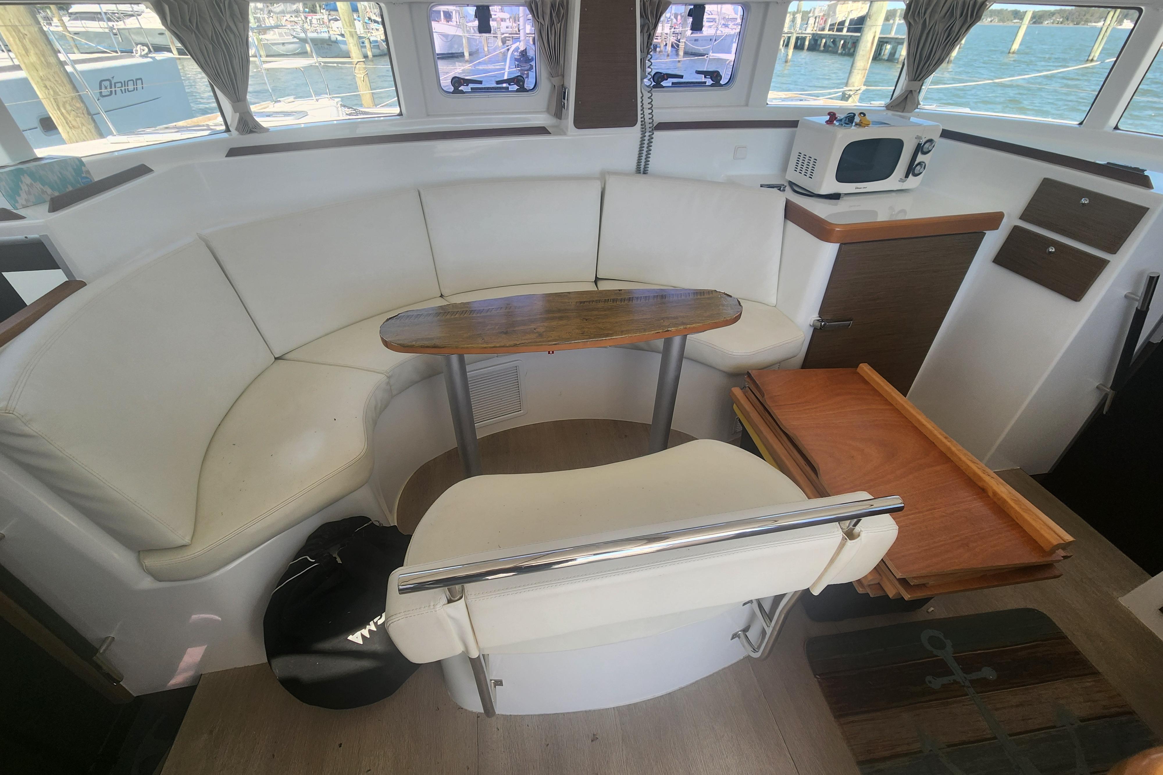 Interior of 2019 Lagoon 380 catamaran with white seating, wooden table, and nautical decor.