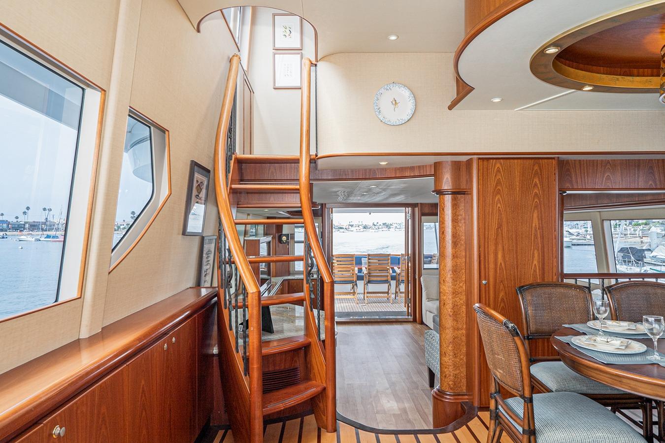 Luxurious 2003 West Bay Sonship yacht interior with elegant wood staircase and dining area.