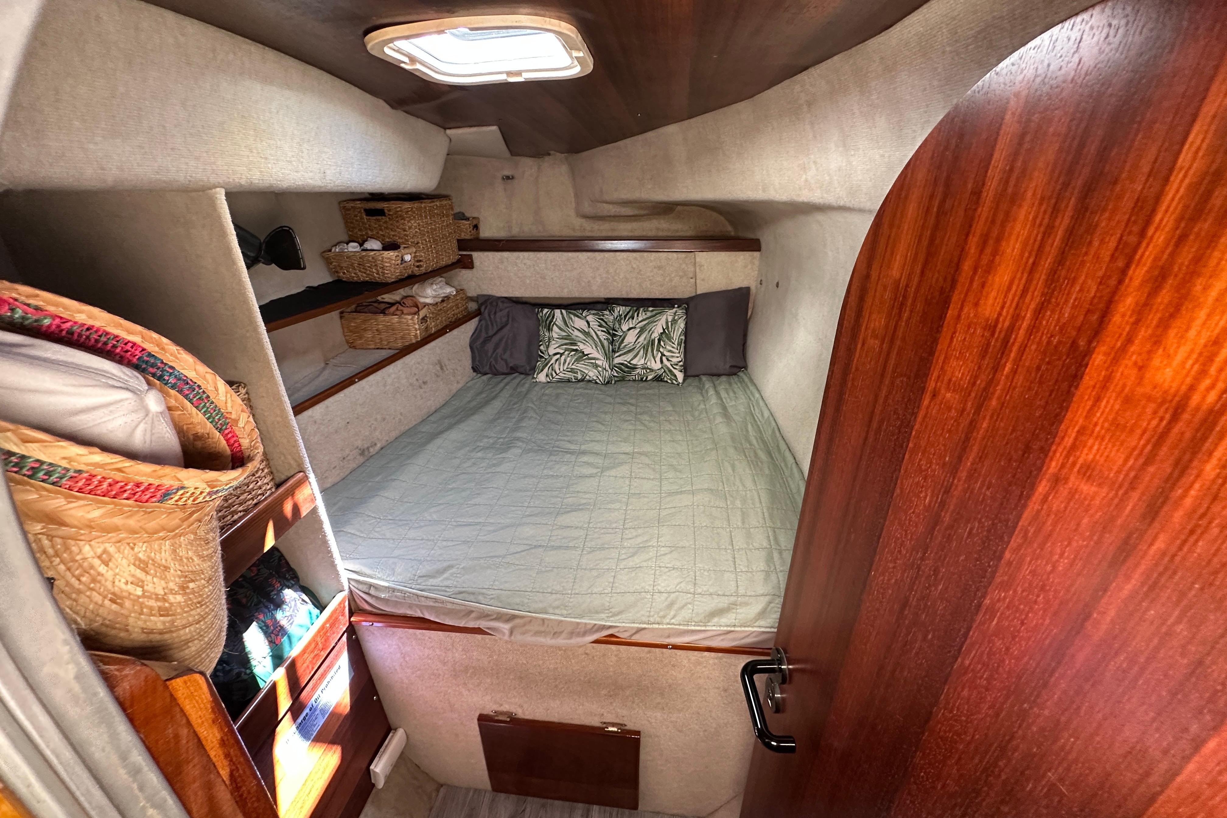 Cozy cabin interior of 1995 Fountaine Pajot Athena 38 catamaran with bed and storage.