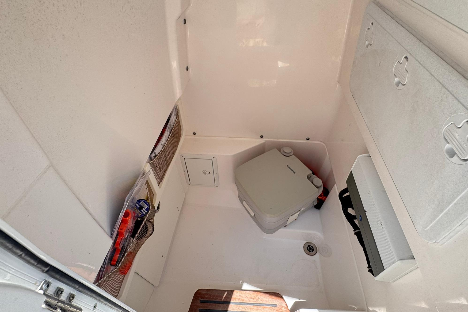 Interior of 2018 Everglades 253 Center Console boat, featuring storage and portable toilet.