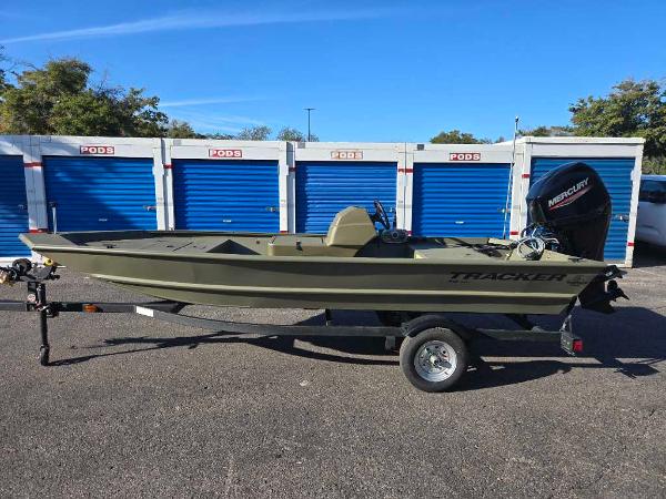 2025 Tracker Grizzly 1648 SC boat on trailer, parked near storage units.