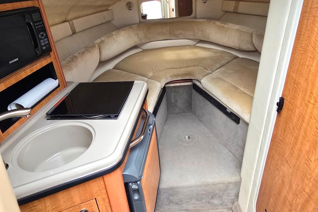 Interior of 2006 Sea Ray 240 Sundancer boat with kitchenette and cozy seating area.