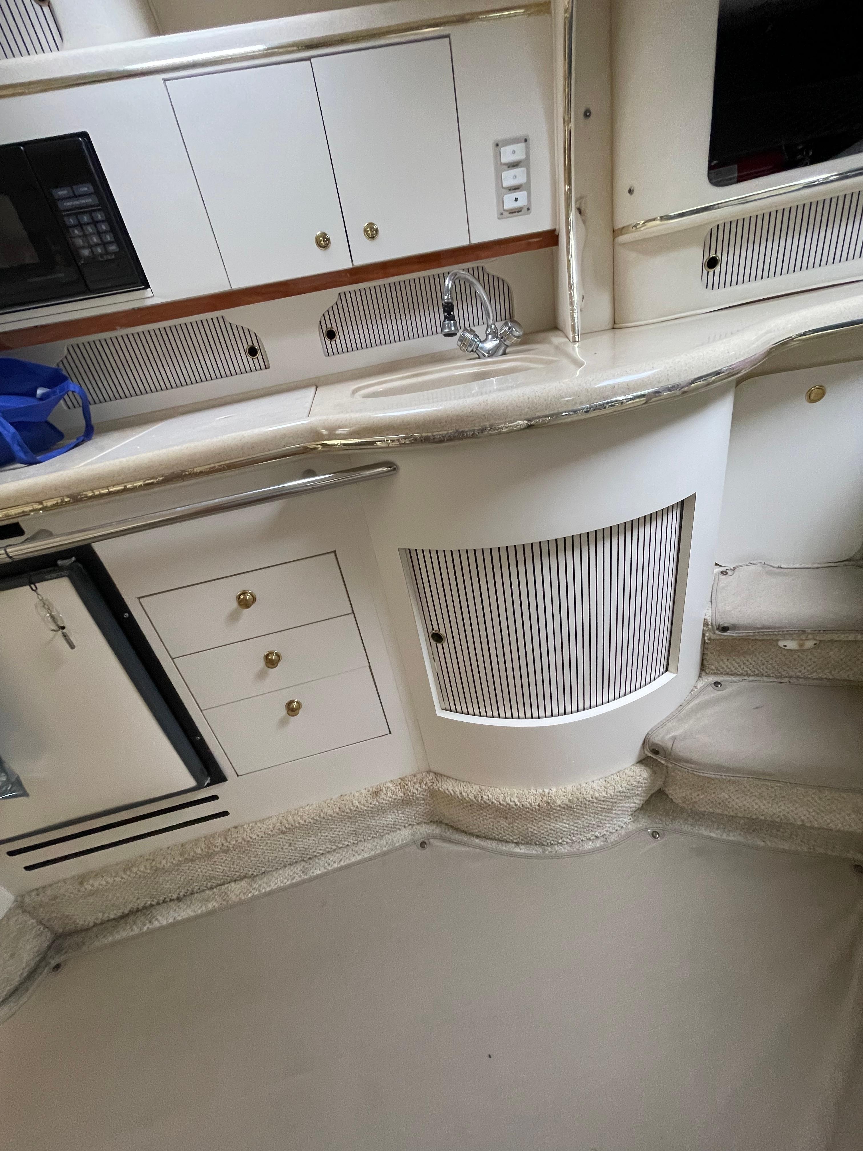 2001 Sea Ray 310 Sundancer interior with kitchenette and storage cabinets.