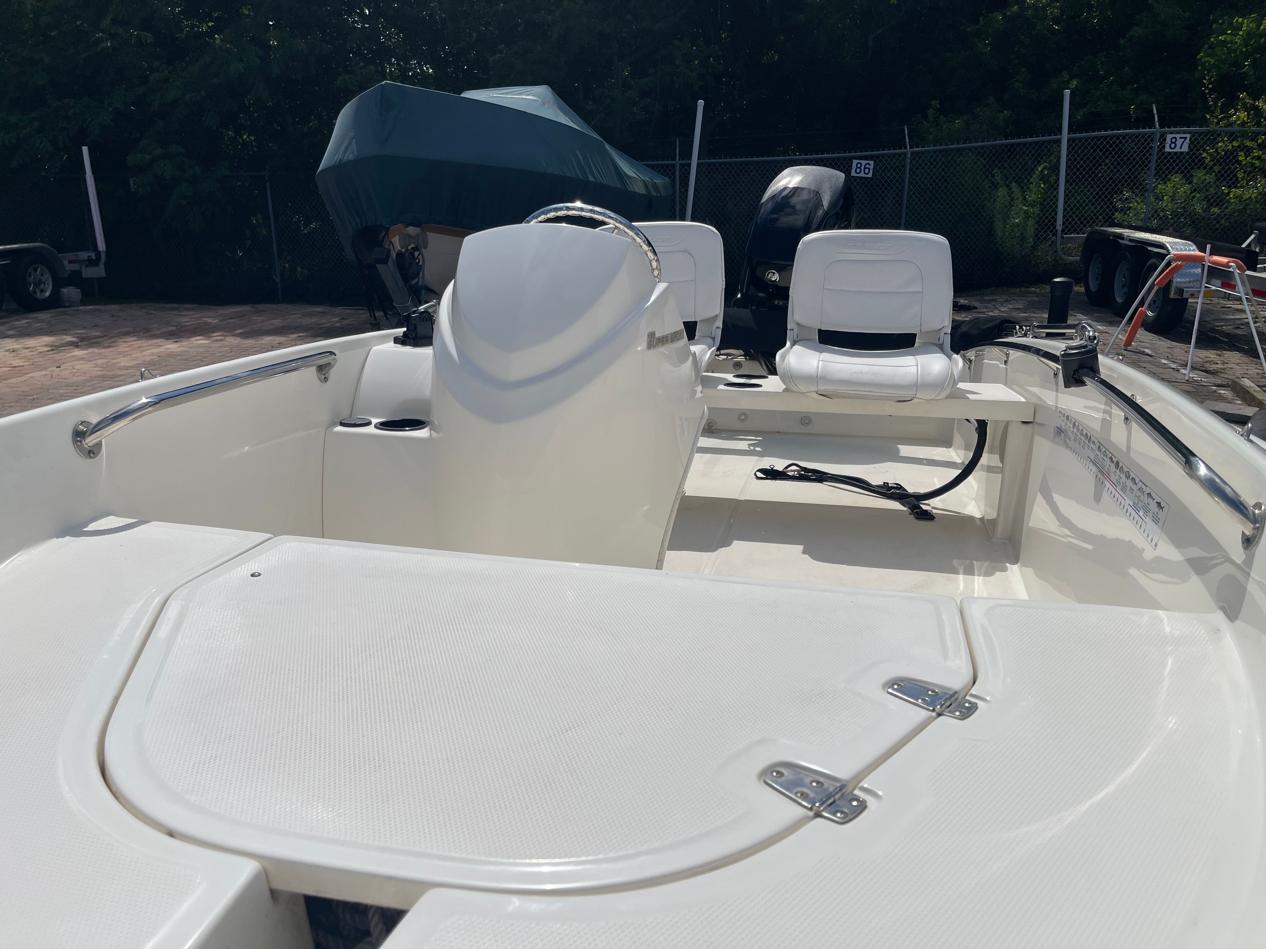 The image shows a 2017 Boston Whaler 130 Super Sport boat. It features white seating and a simple design.