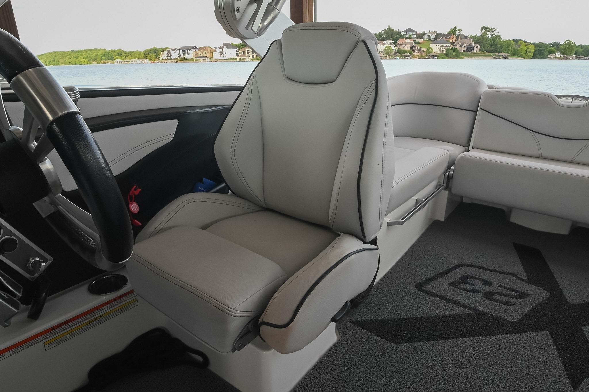 2018 MasterCraft X23 boat interior with luxurious seating and steering wheel, overlooking a scenic lake.