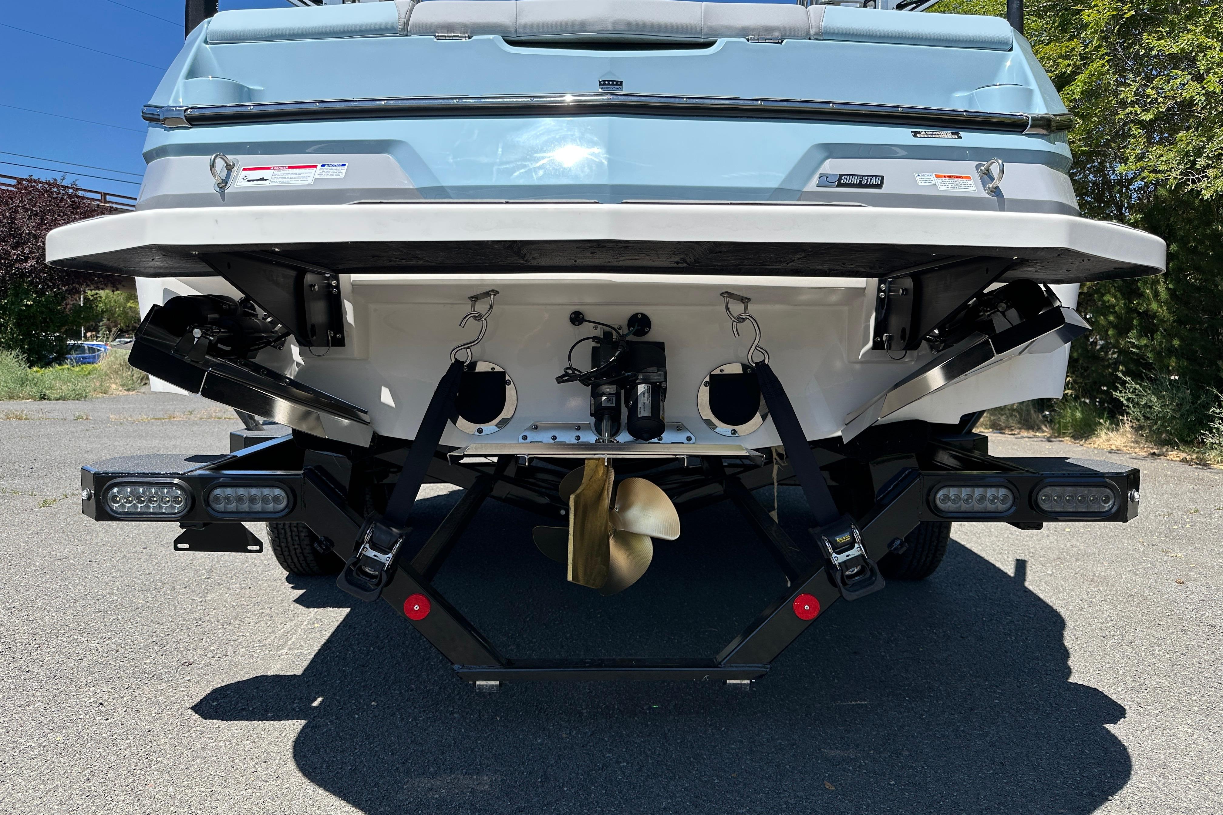 2023 MasterCraft NXT23 boat rear view, showcasing propeller and surf system features.
