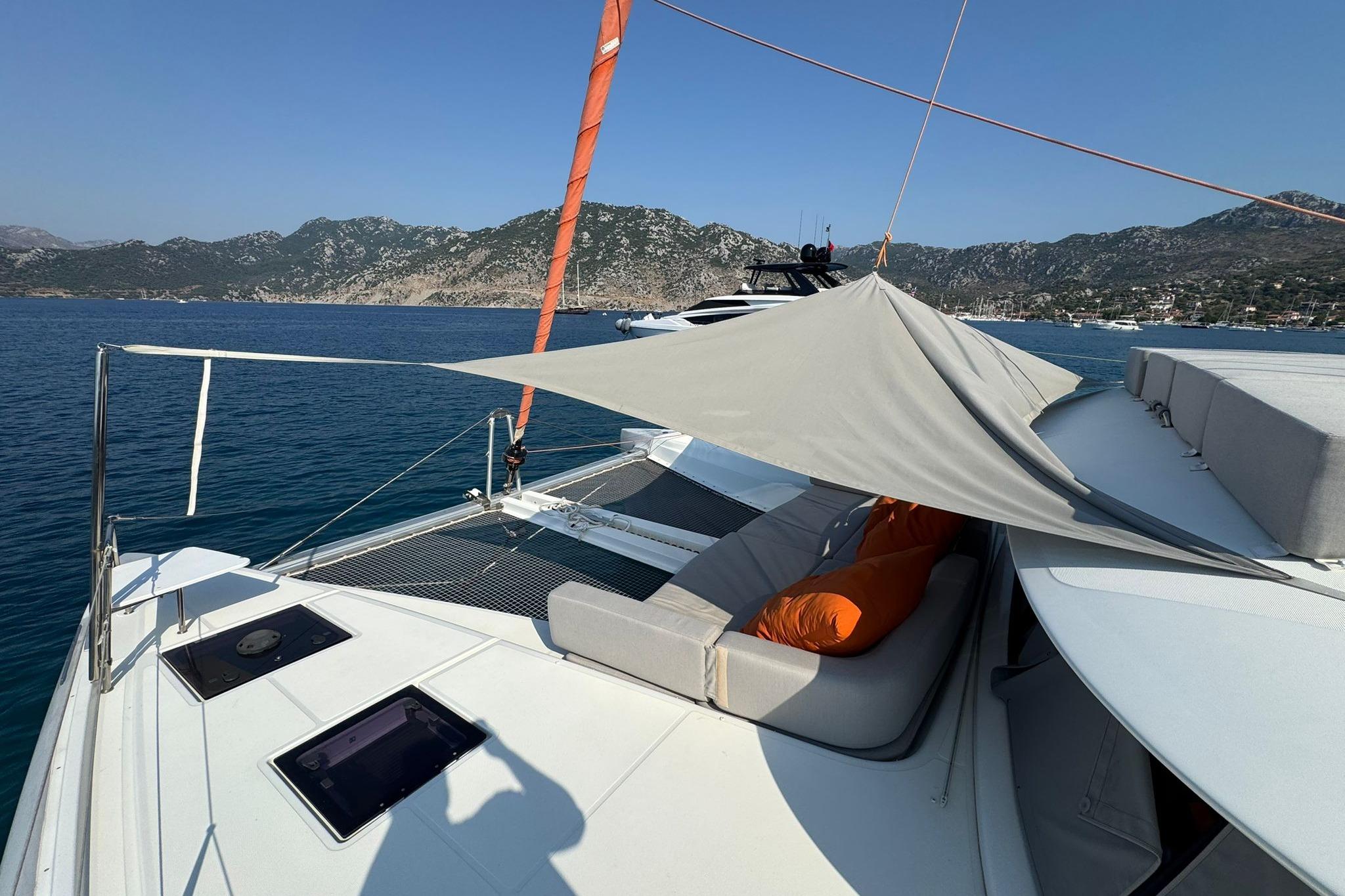 Luxurious 2021 Excess 15 yacht with sunshade, cushions, and scenic coastal backdrop.