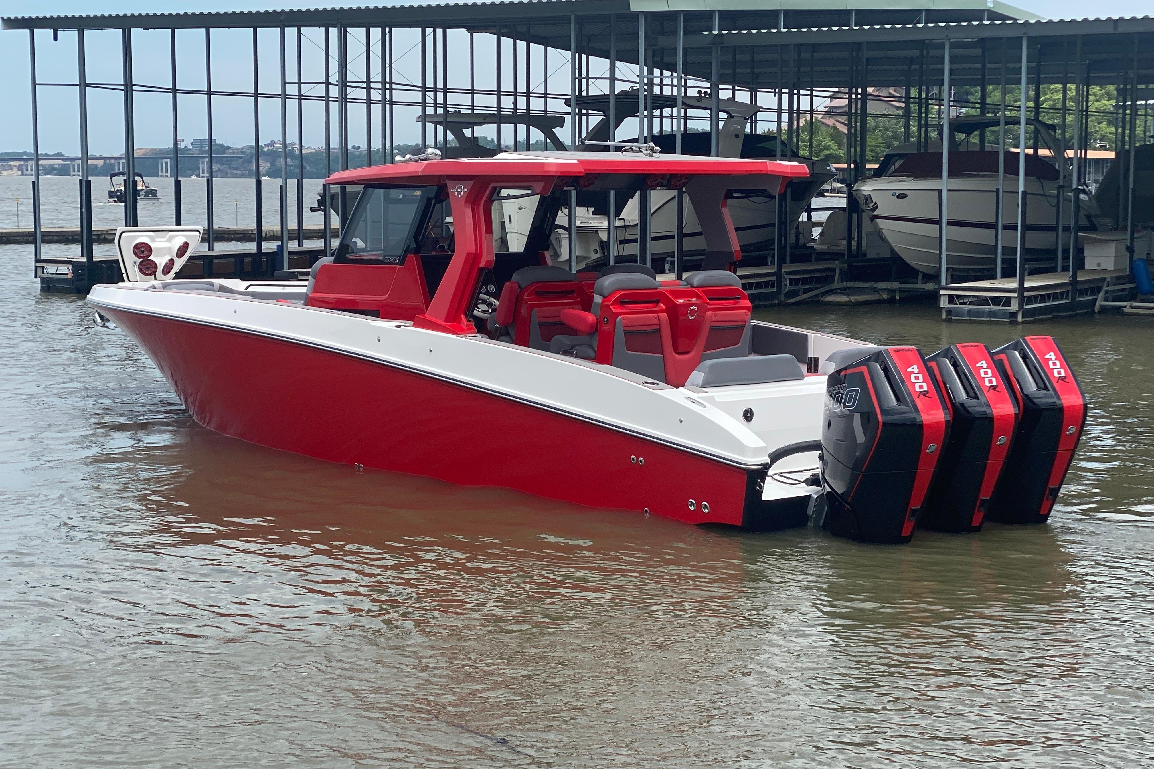 2025 Fountain 38 SCX boat with red and white design, docked on a calm lake.