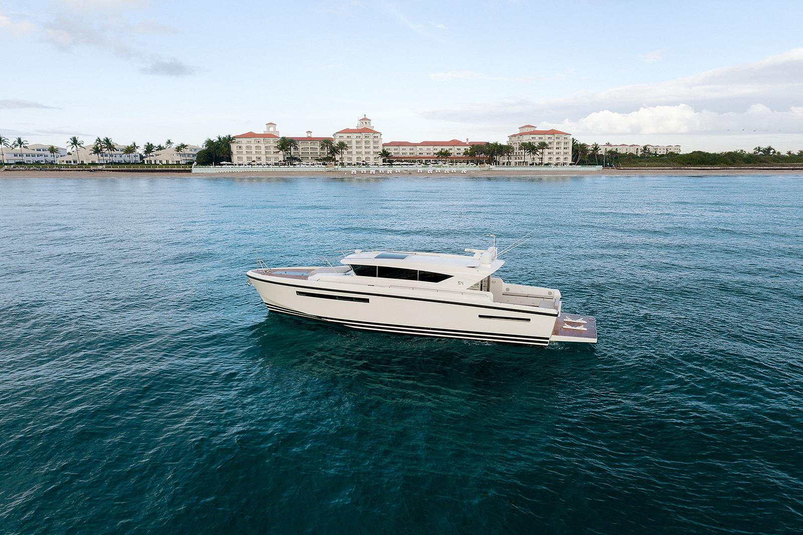 2023 Delta Powerboats 54 IPS yacht cruising near a coastal resort.