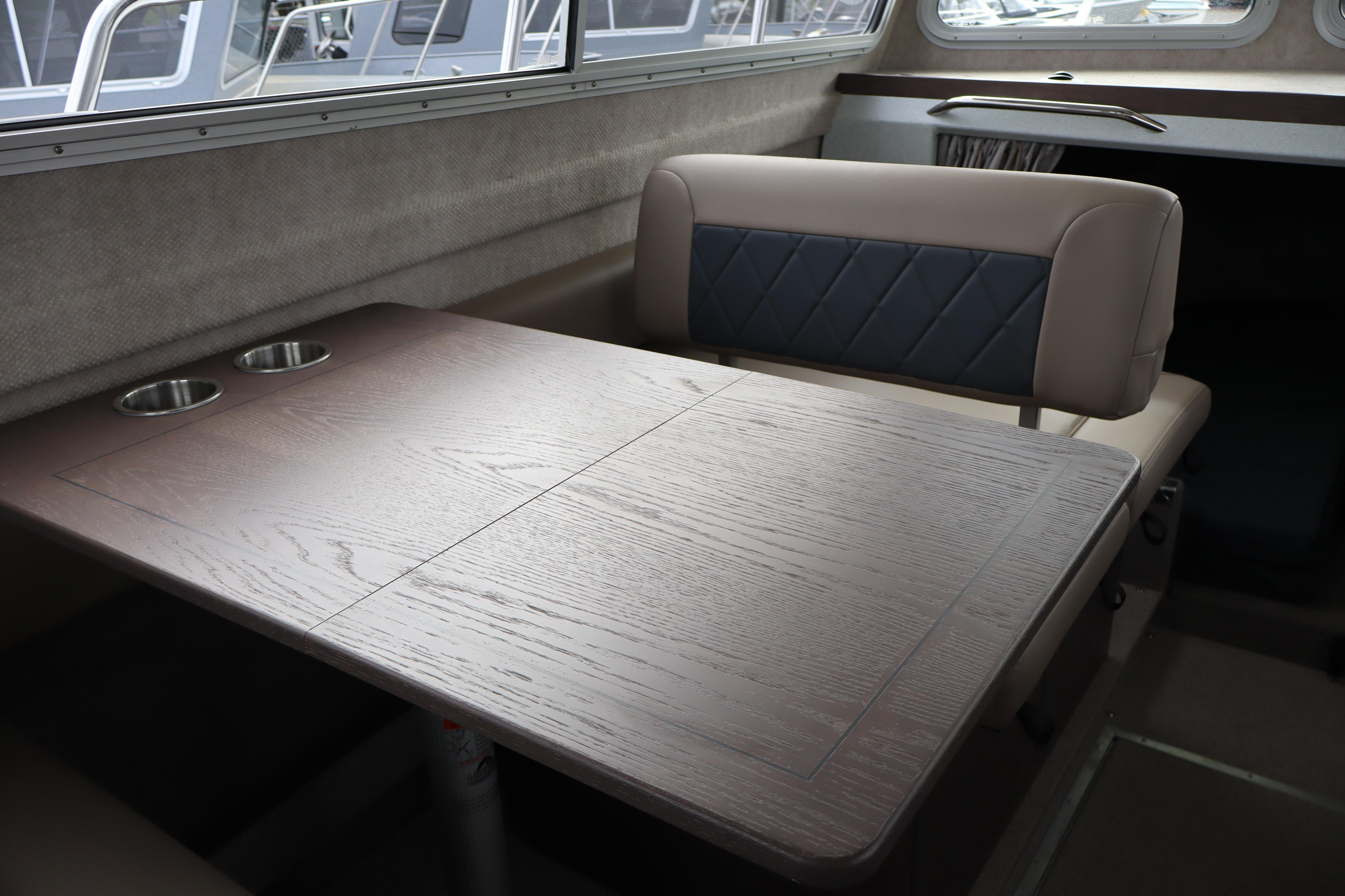 Interior of 2026 KingFisher 3025 XRS boat with wooden table and cushioned seating.