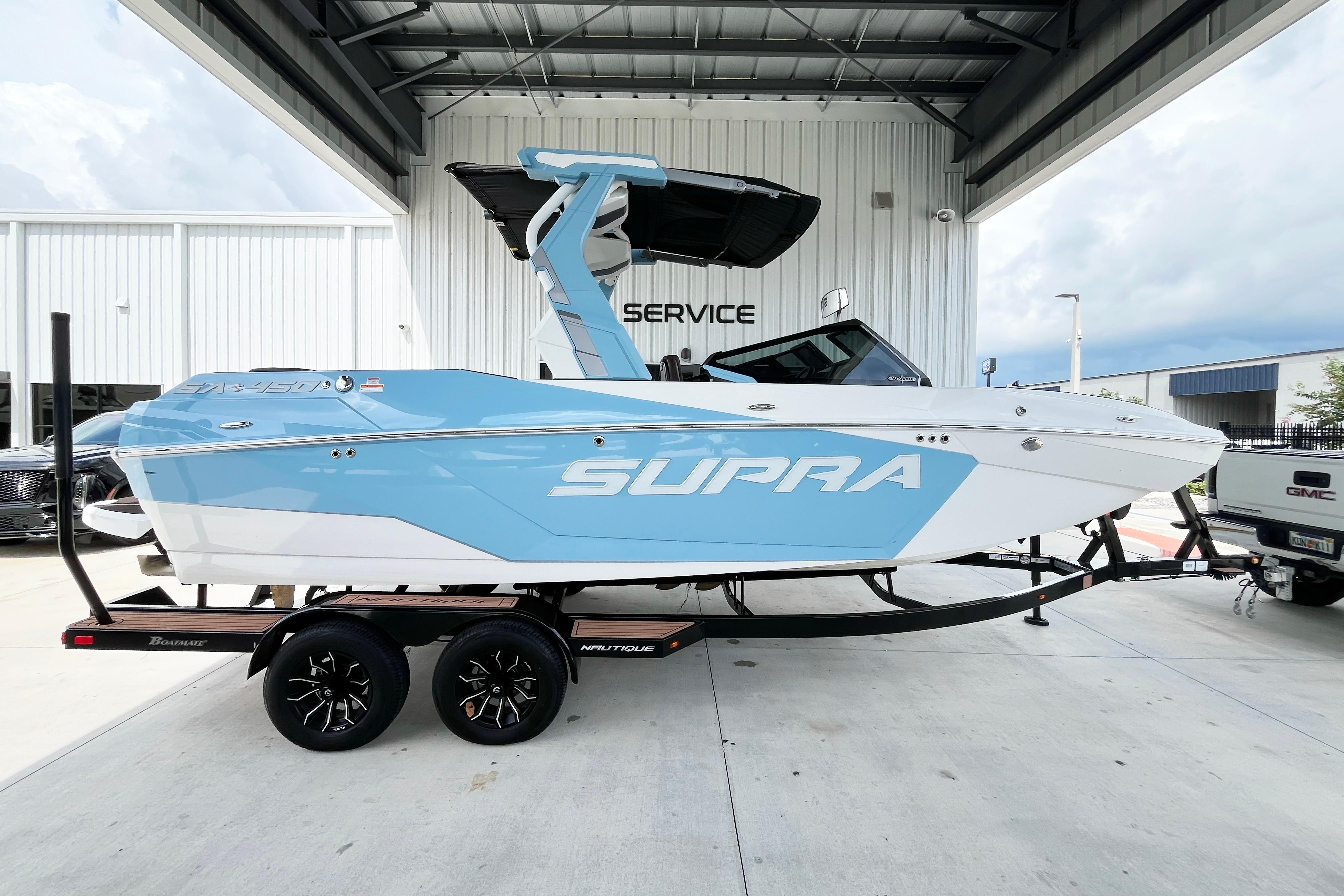 2025 Supra SA450 boat on trailer, blue and white design, parked at service center.