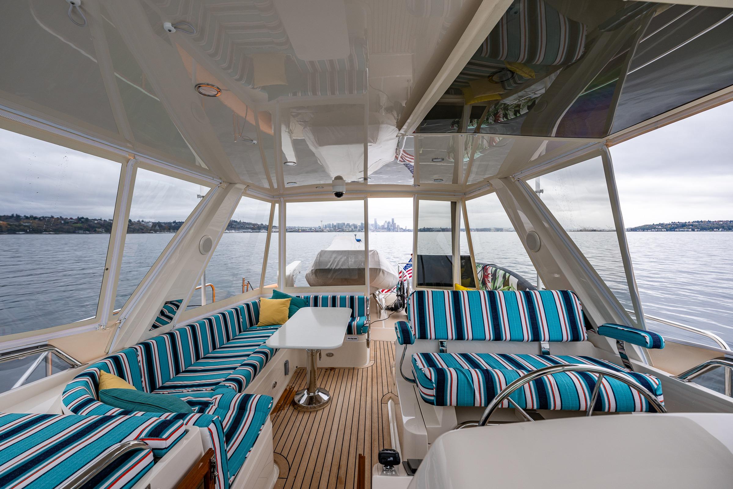 Luxurious 2026 Fleming 55 Pilothouse yacht interior with striped seating and scenic water view.