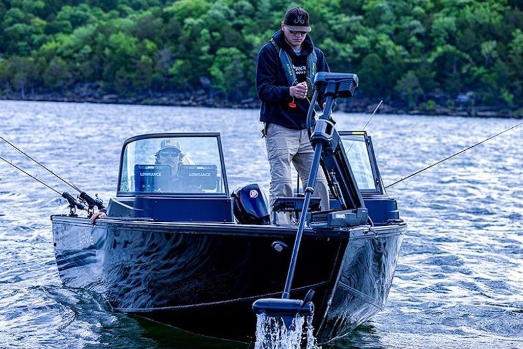 2026 Lowe Fishing Machine 1875 on a lake, two people fishing, surrounded by lush greenery.