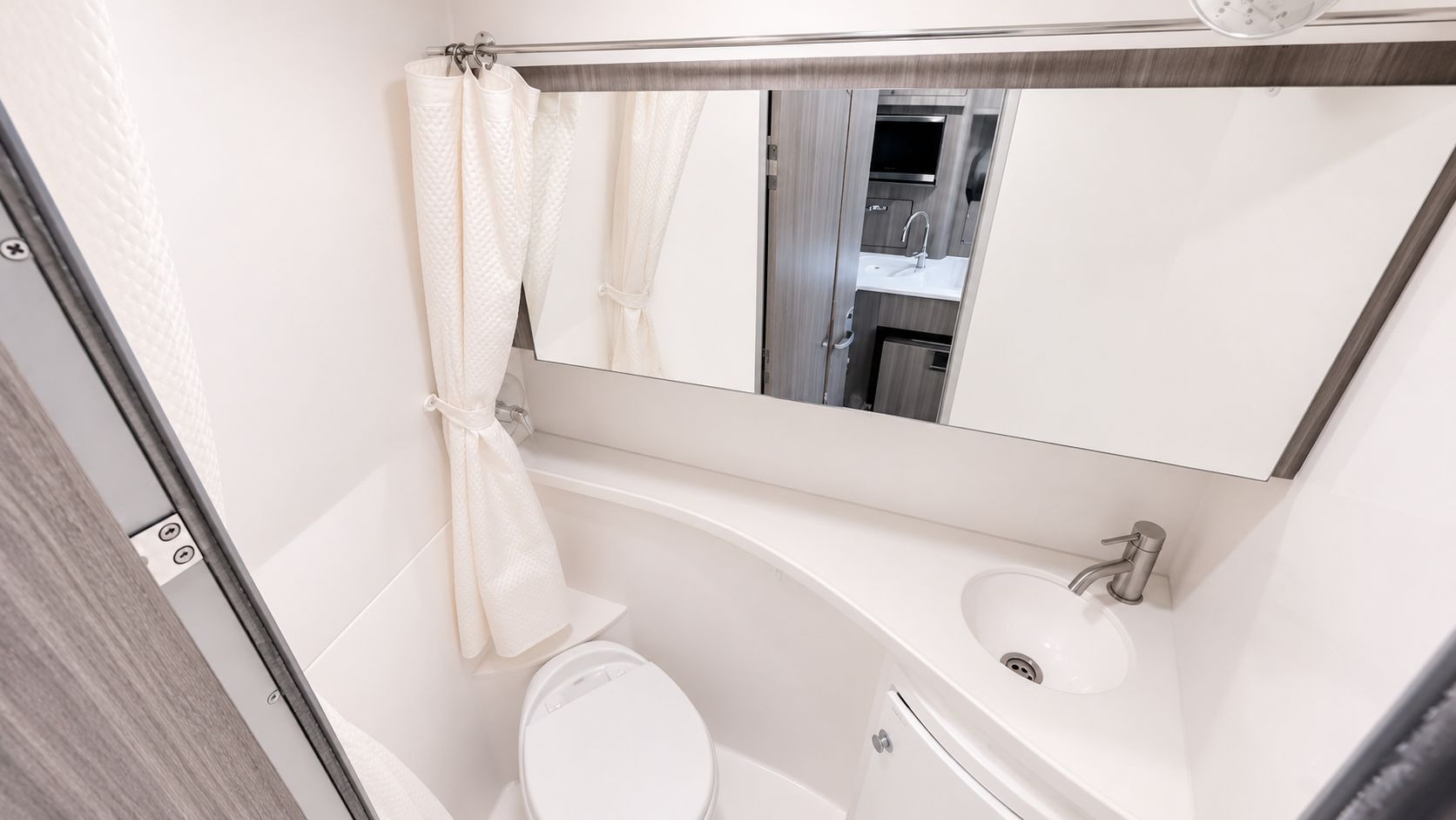 Bathroom in a Regal 28 Express boat, featuring a toilet, sink, and mirror.