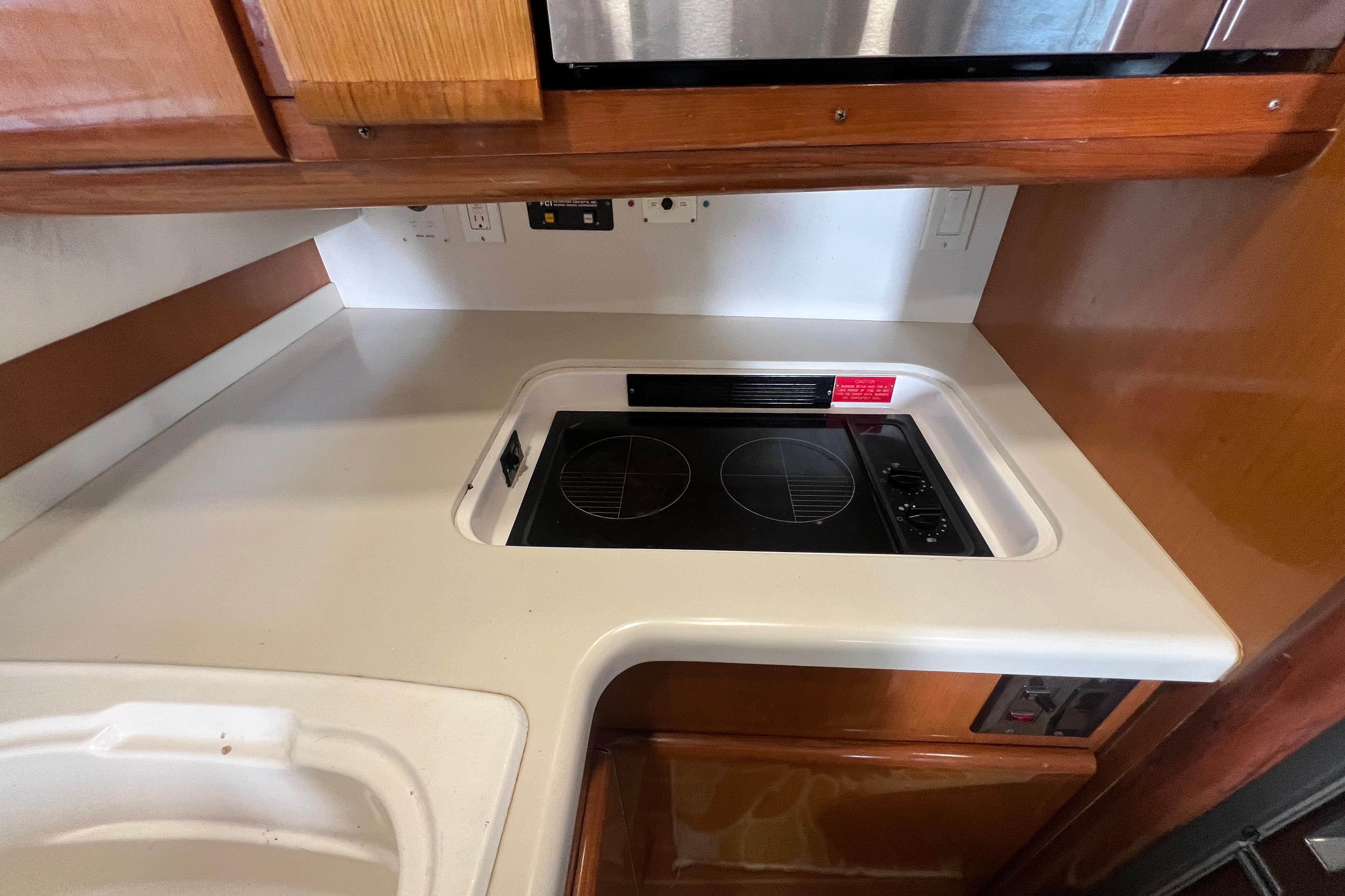 1999 Viking 60 CPMY yacht kitchen with electric stove and wooden cabinetry.