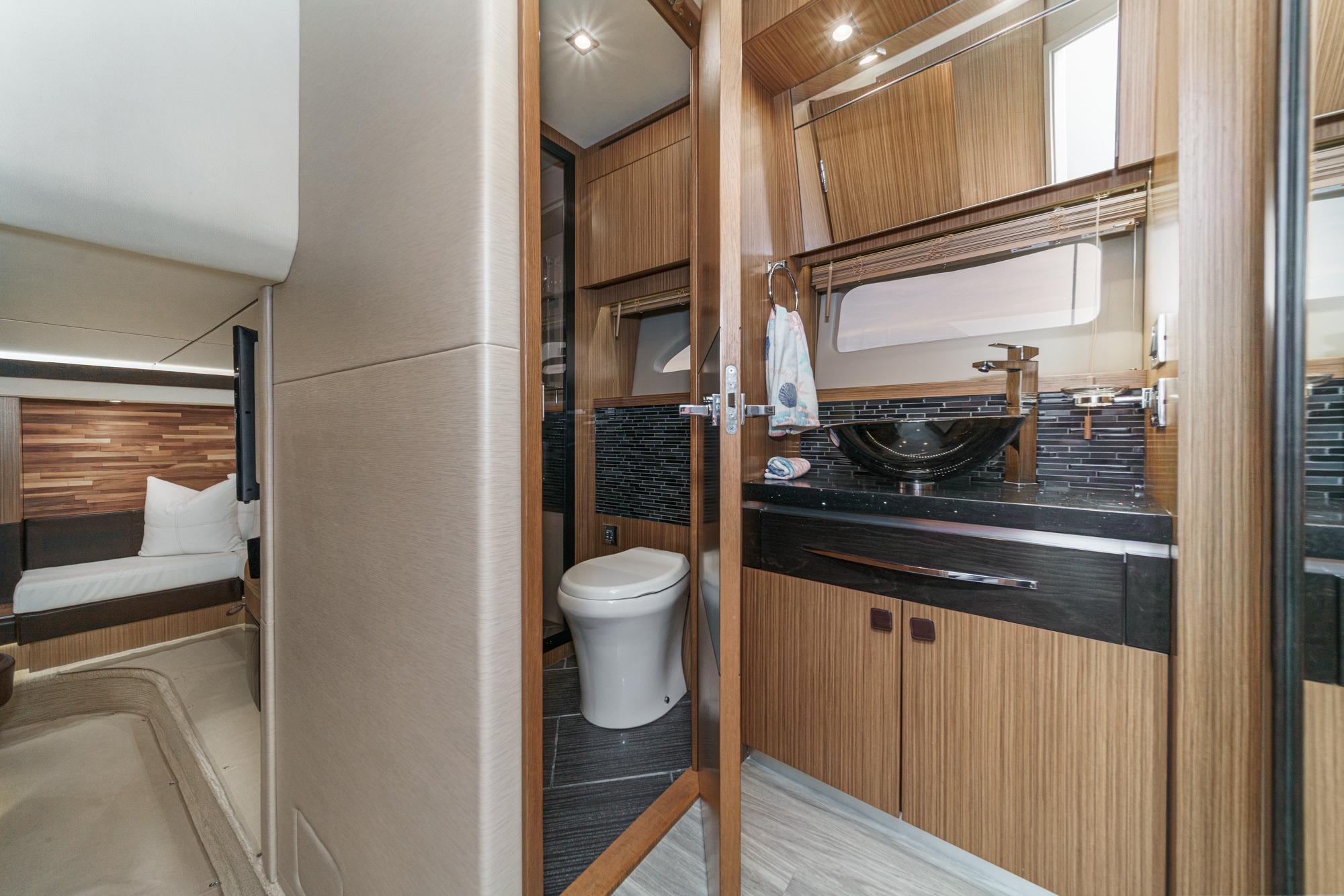 Luxurious 2016 Sea Ray L590 yacht interior with modern bathroom and cozy bedroom.