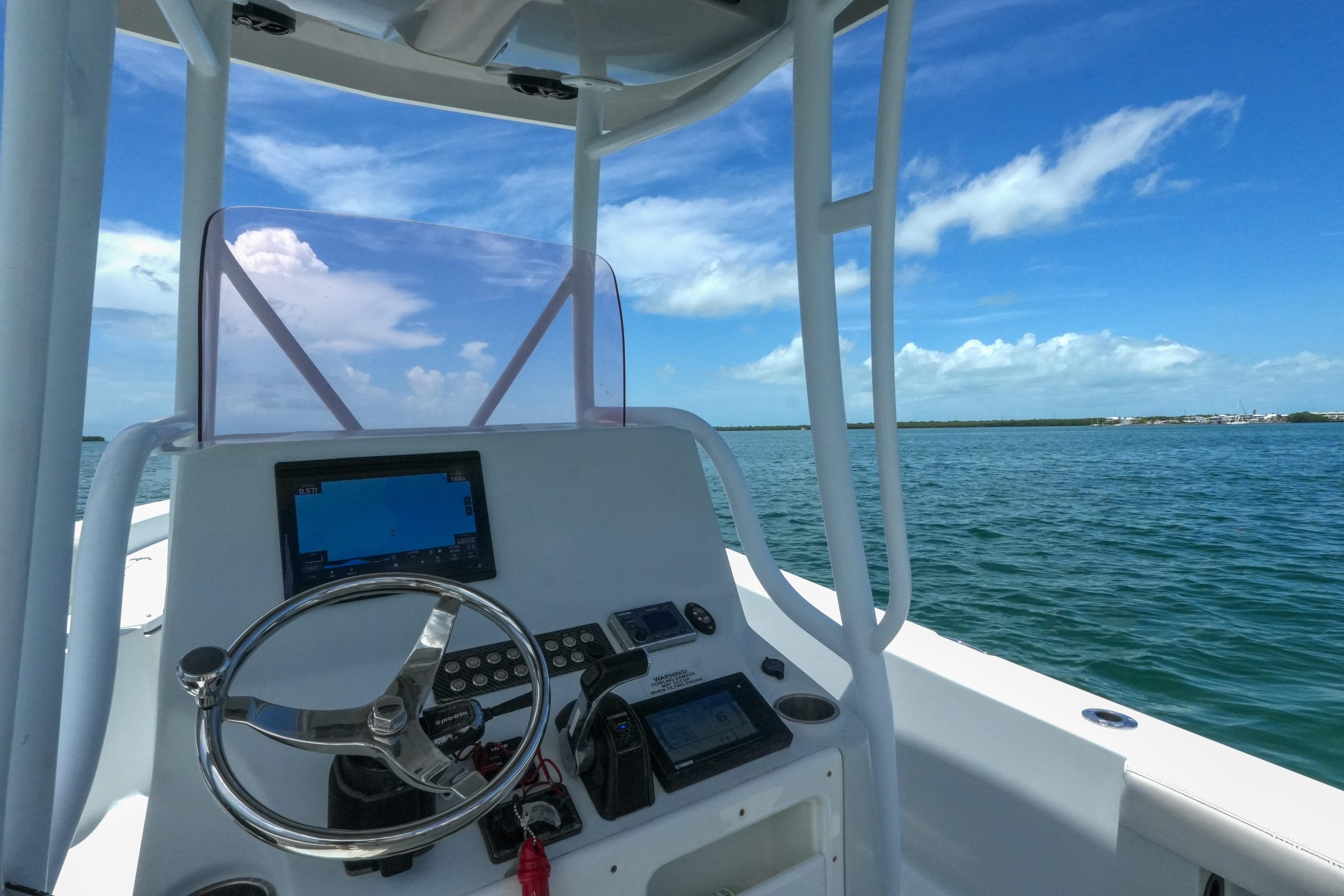 2019 Blue Wave 2800 Pure Hybrid boat dashboard with steering wheel, GPS, and ocean view.