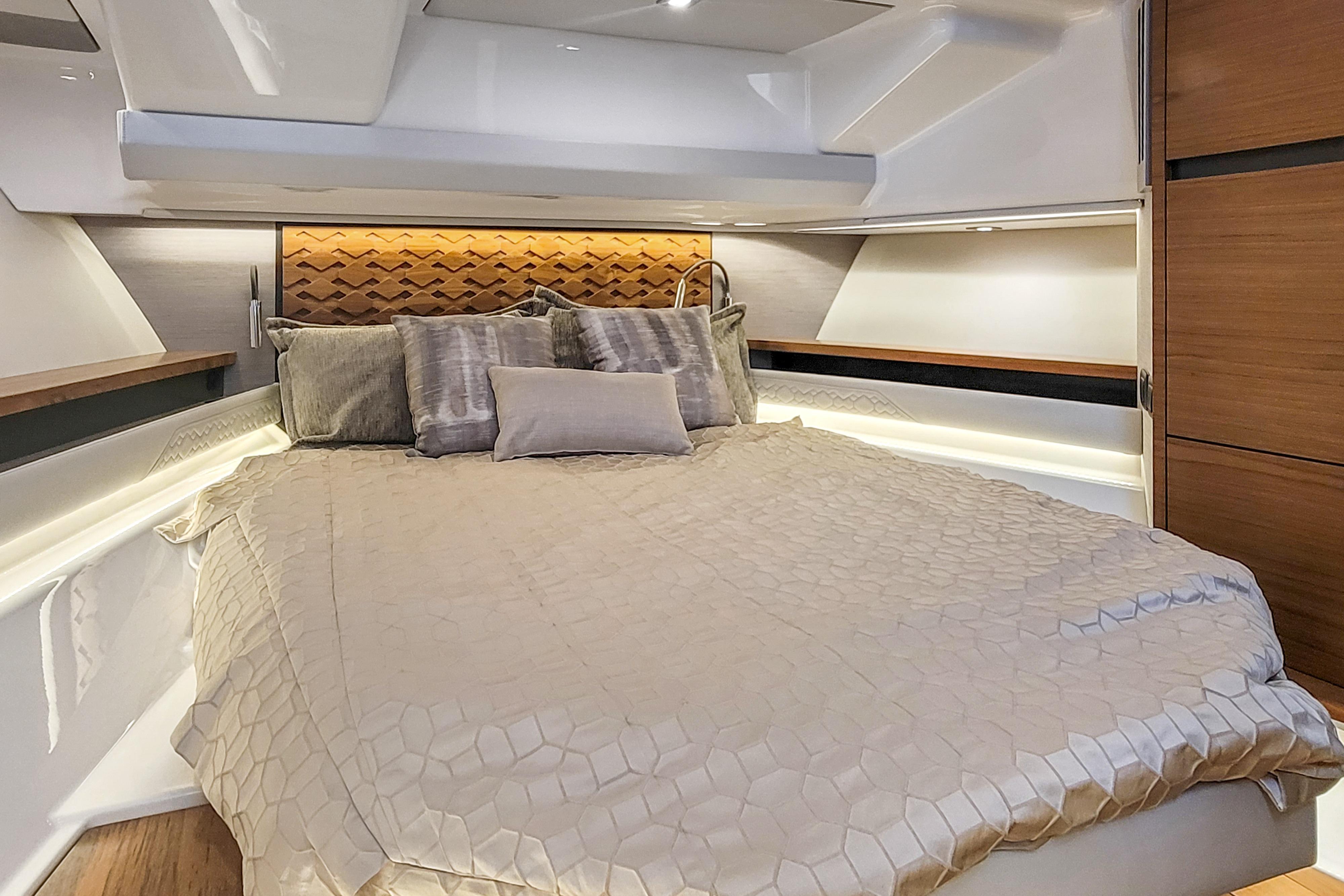 Luxurious bedroom interior of 2022 Tiara Yachts 48 LS with elegant bedding and ambient lighting.