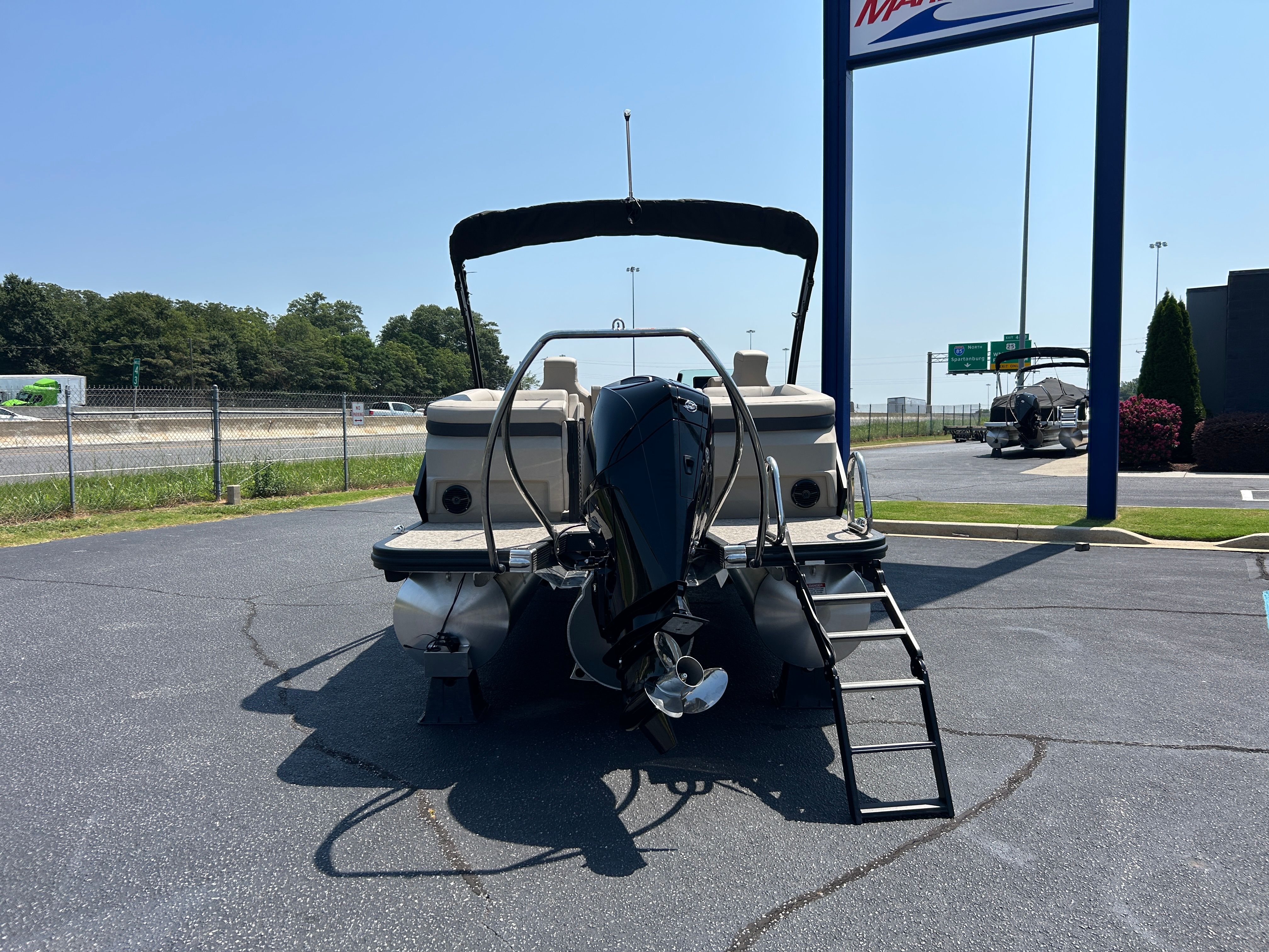 A Bennington 22 MFB pontoon boat is parked on a lot. It features an outboard motor and ladder.