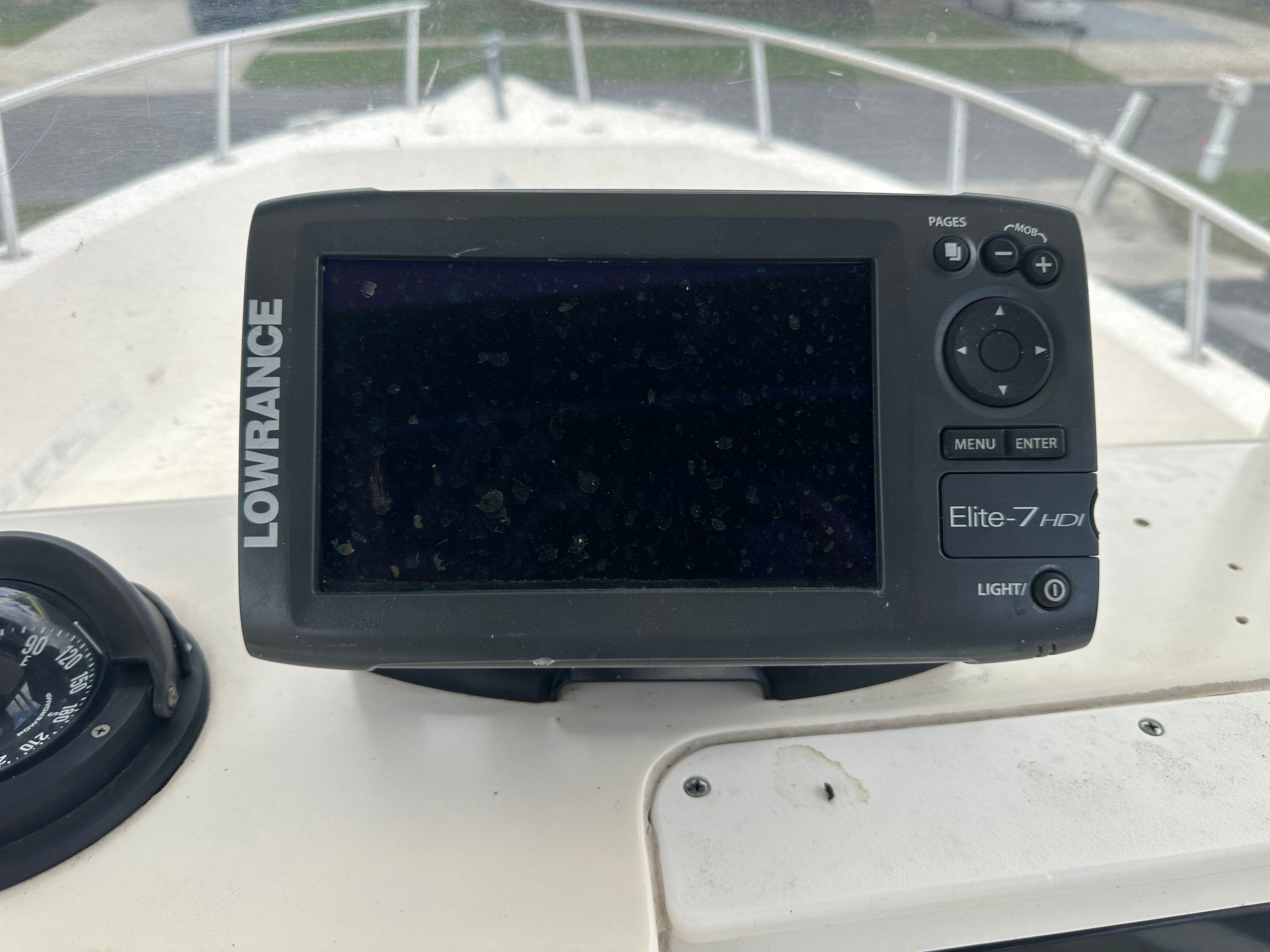 A Lowrance Elite-7 HDI fishfinder mounted on a boat, next to a compass.