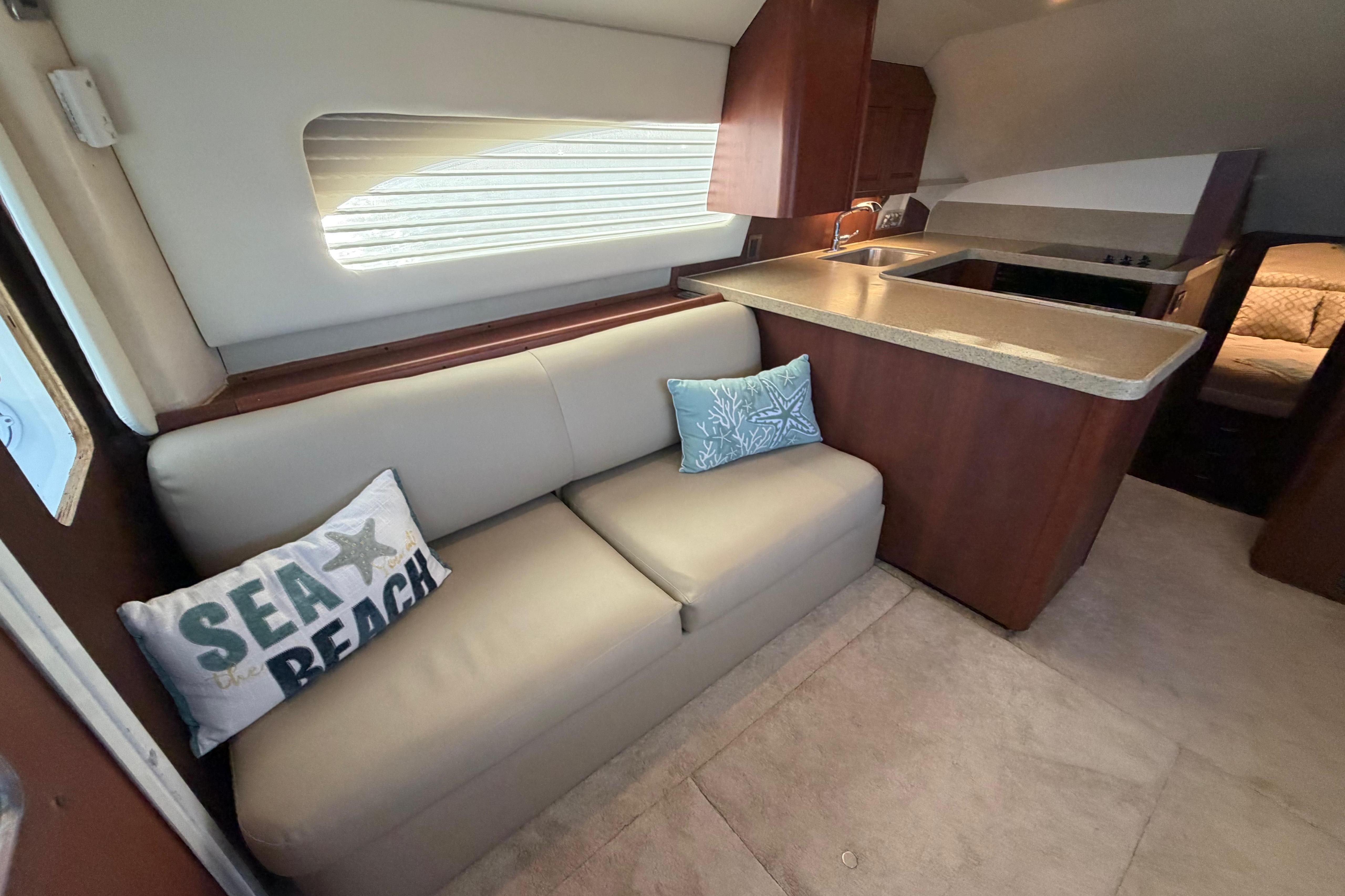 Interior of 2005 Luhrs 38 Convertible yacht with beige sofa and decorative pillows.