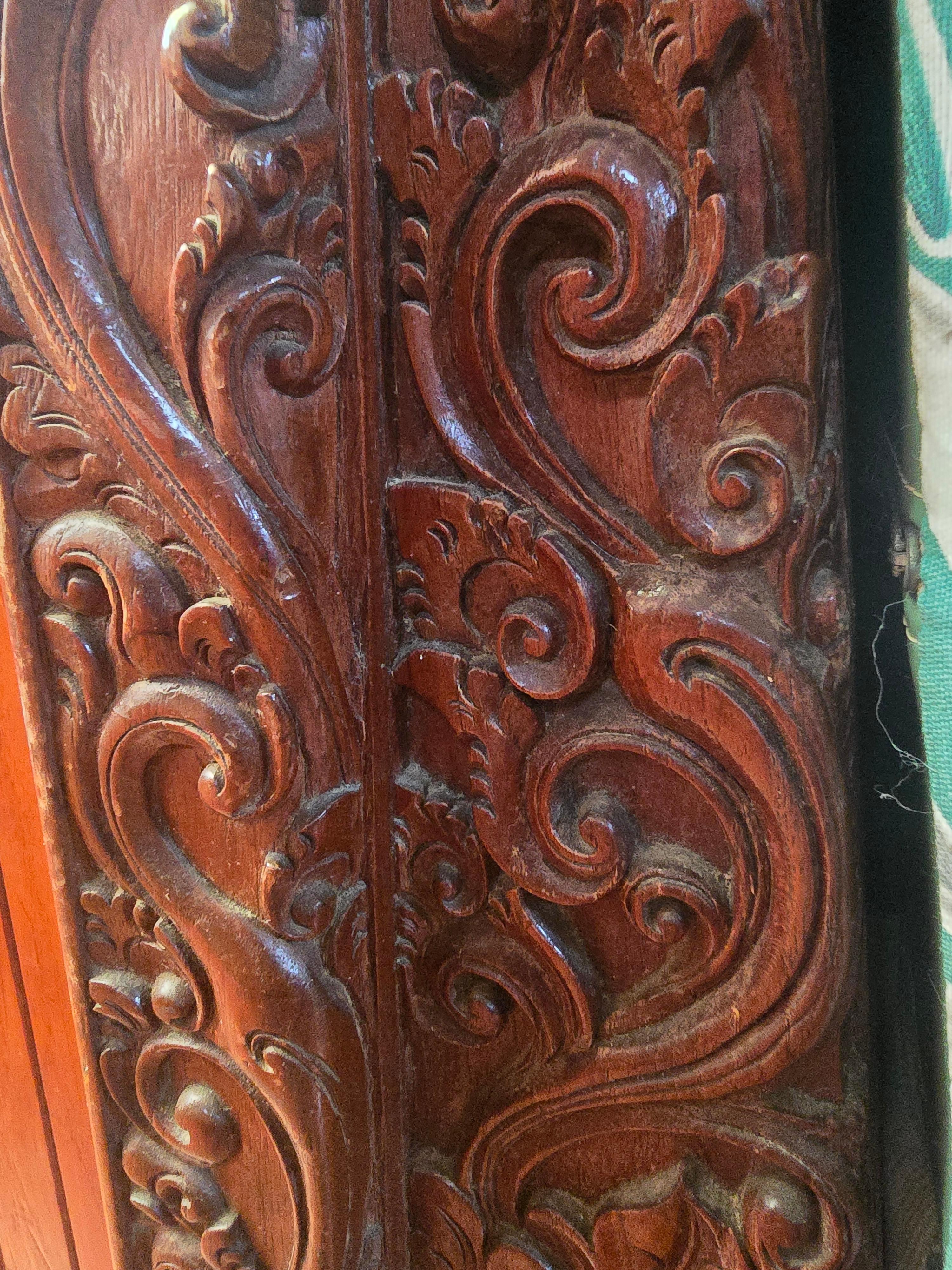 Intricate wood carving detail on a 1978 Herreshoff 50, showcasing elegant swirling patterns.