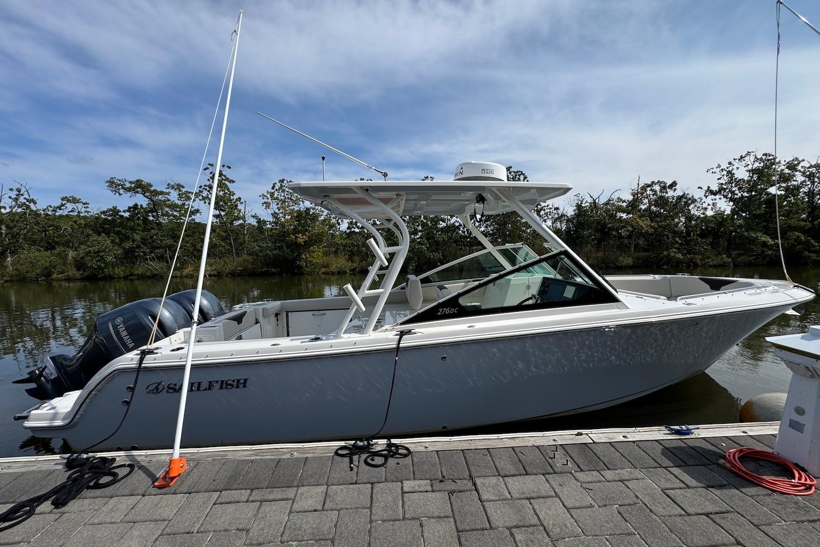 2022 Sailfish 276 DC boat docked by a scenic riverside.