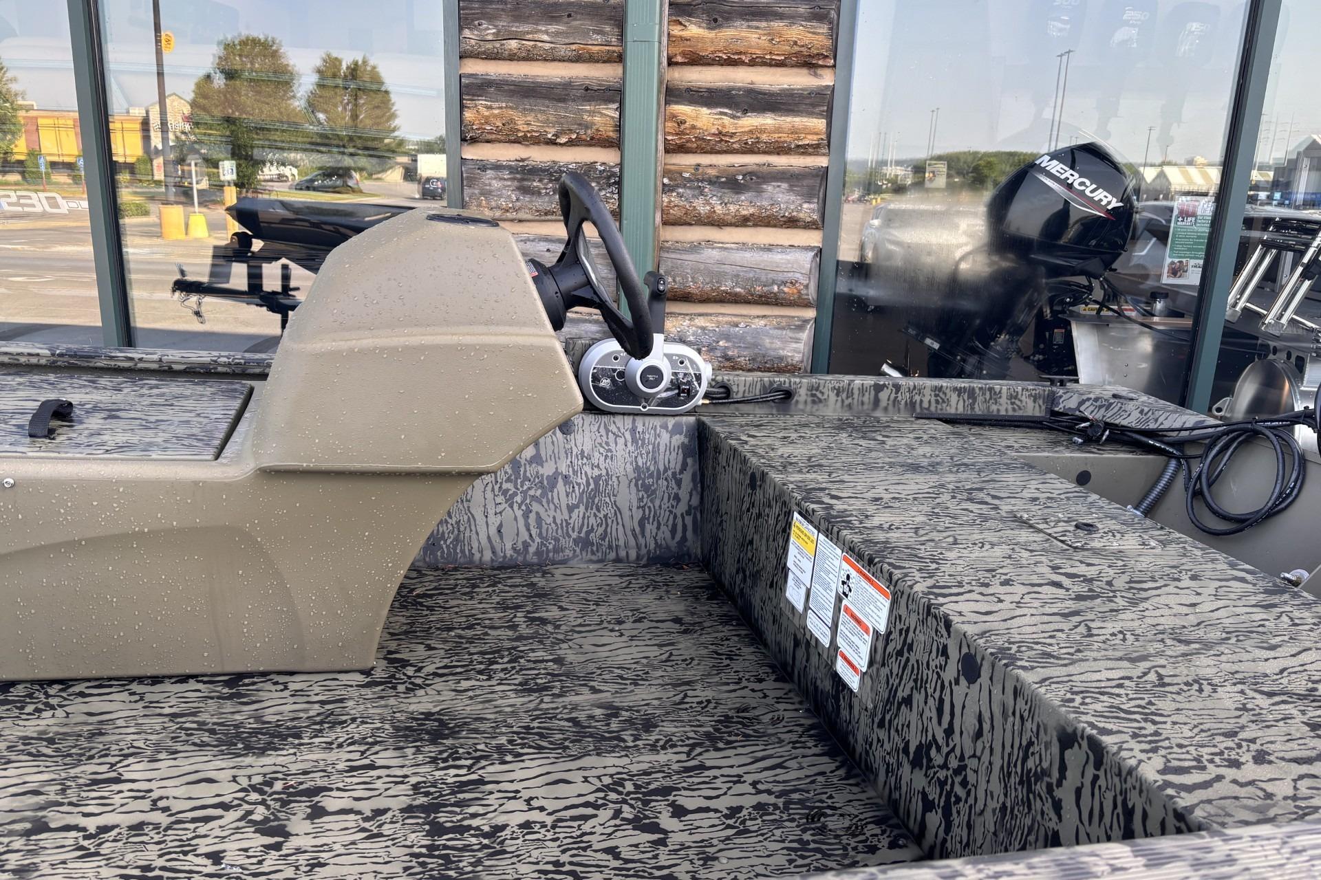 2026 Tracker Grizzly 1648 SC boat interior with steering console and camouflage seating.