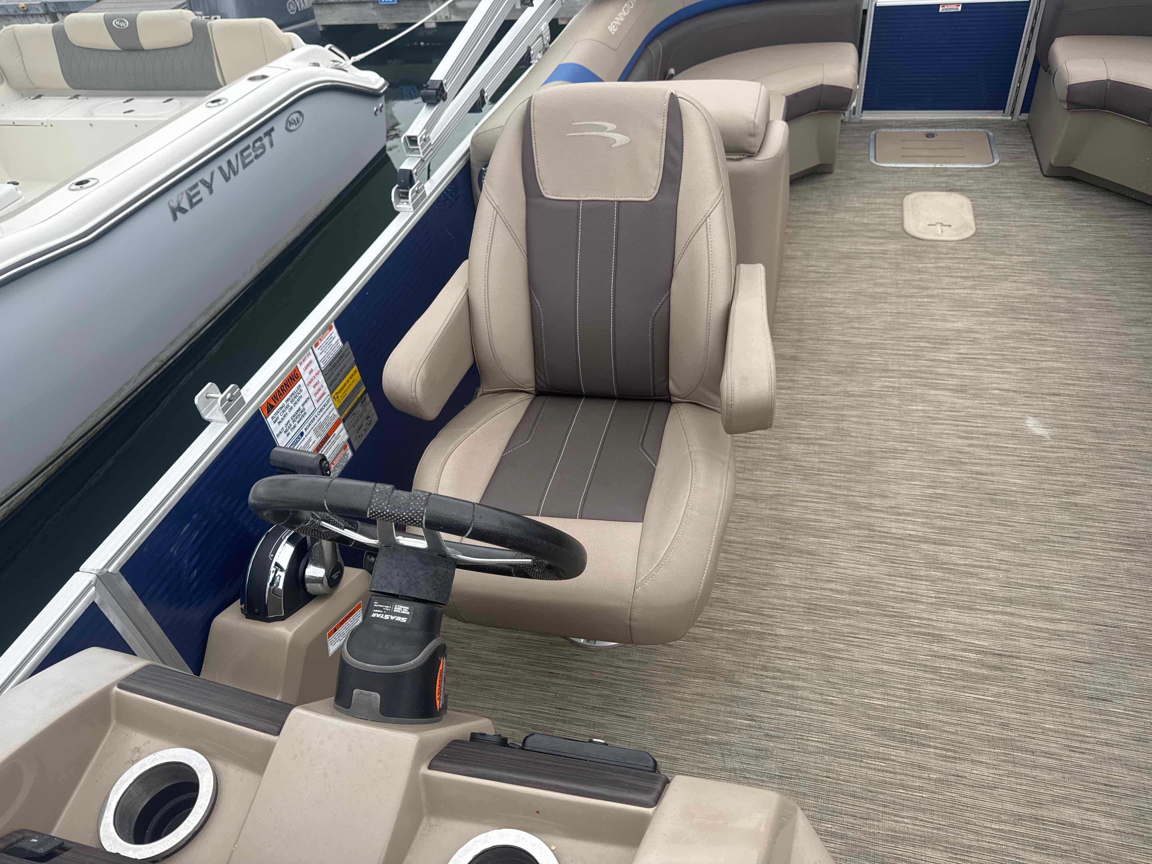 A sleek seating area on a Bennington 23SXSRC pontoon boat with comfortable seats and a helm console.
