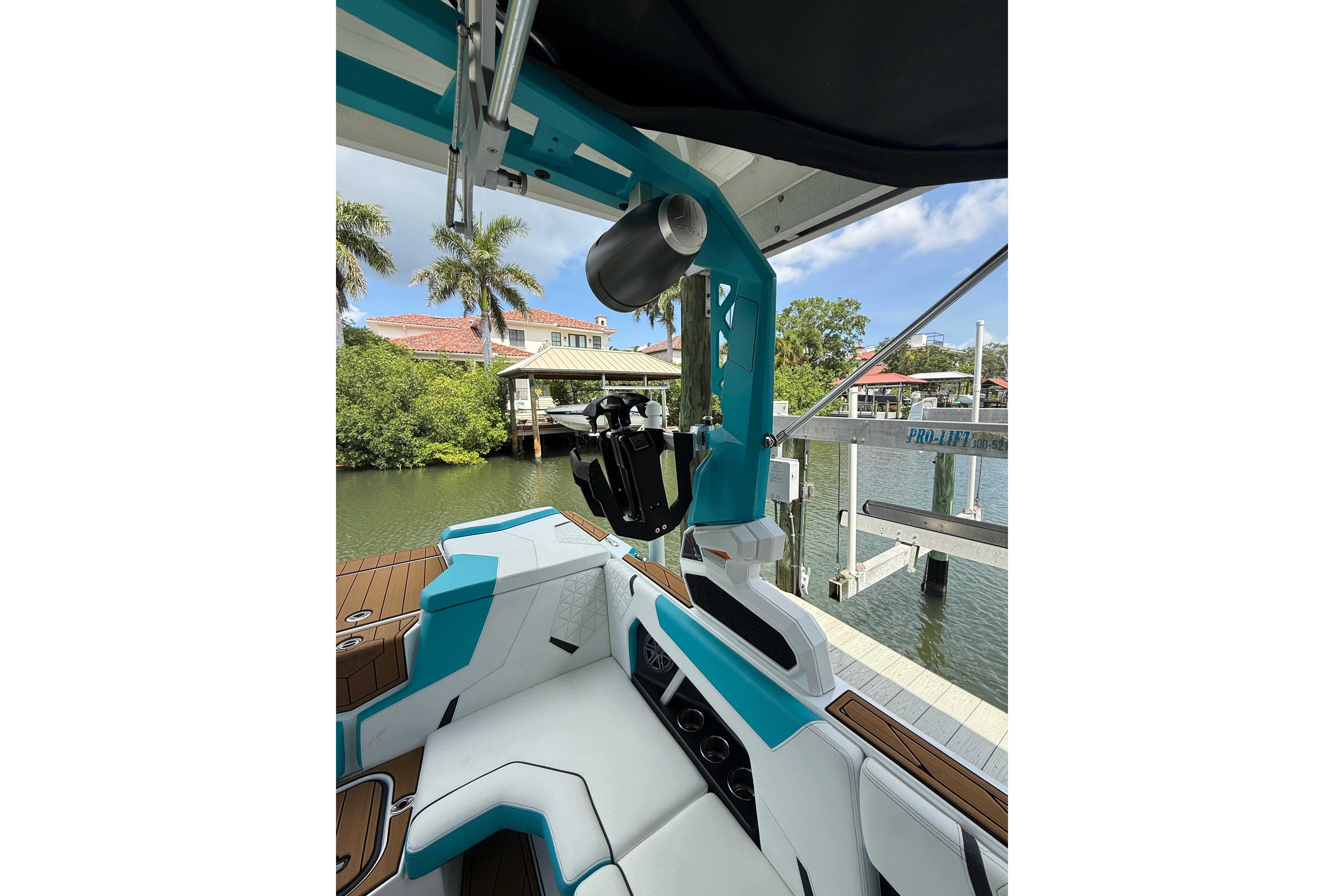 2024 Nautique Super Air Nautique GS20 interior with teal accents, docked by waterfront homes.