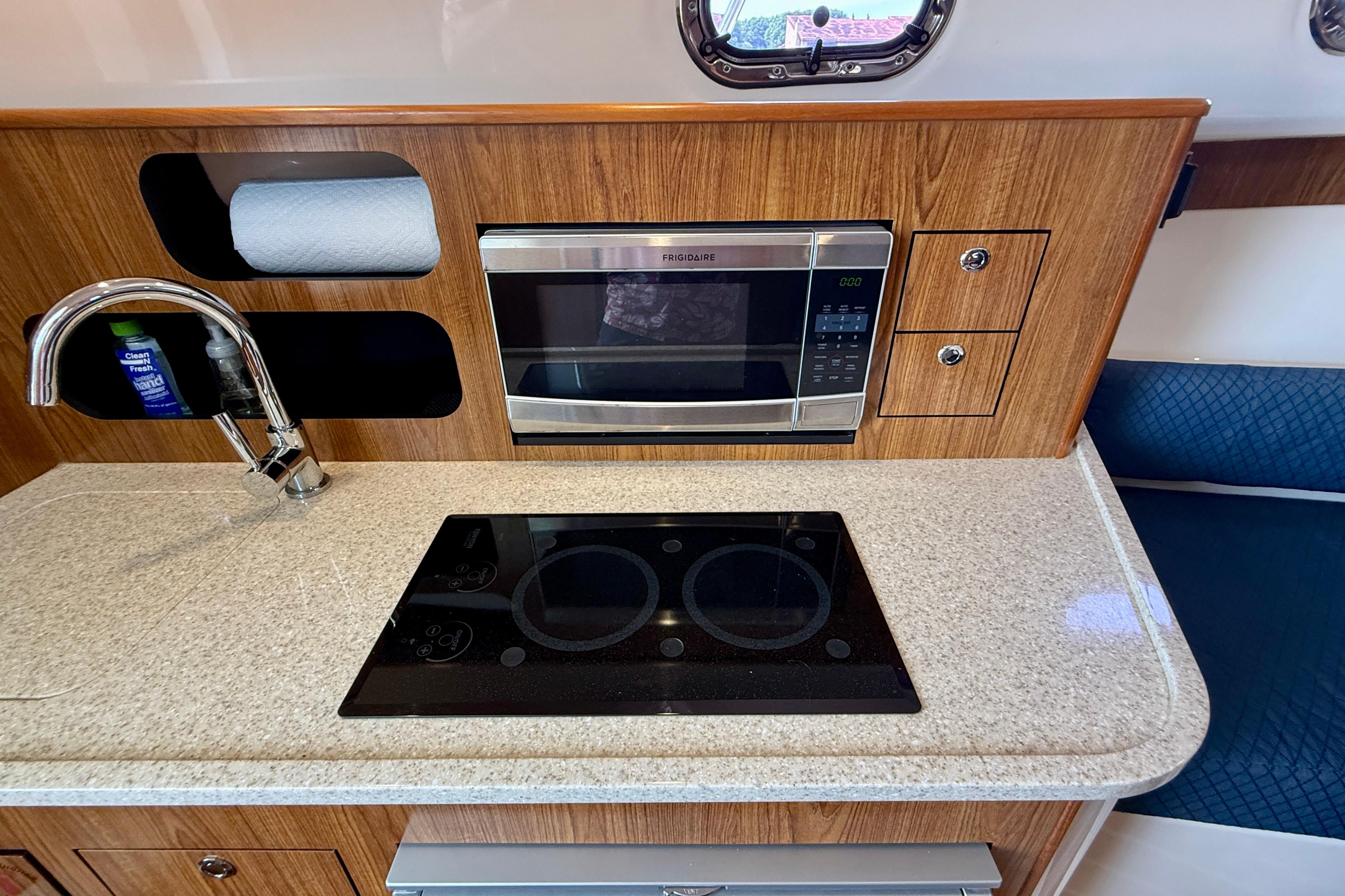 Compact kitchen in 2012 Pursuit OS 345 Offshore boat with microwave and stovetop.