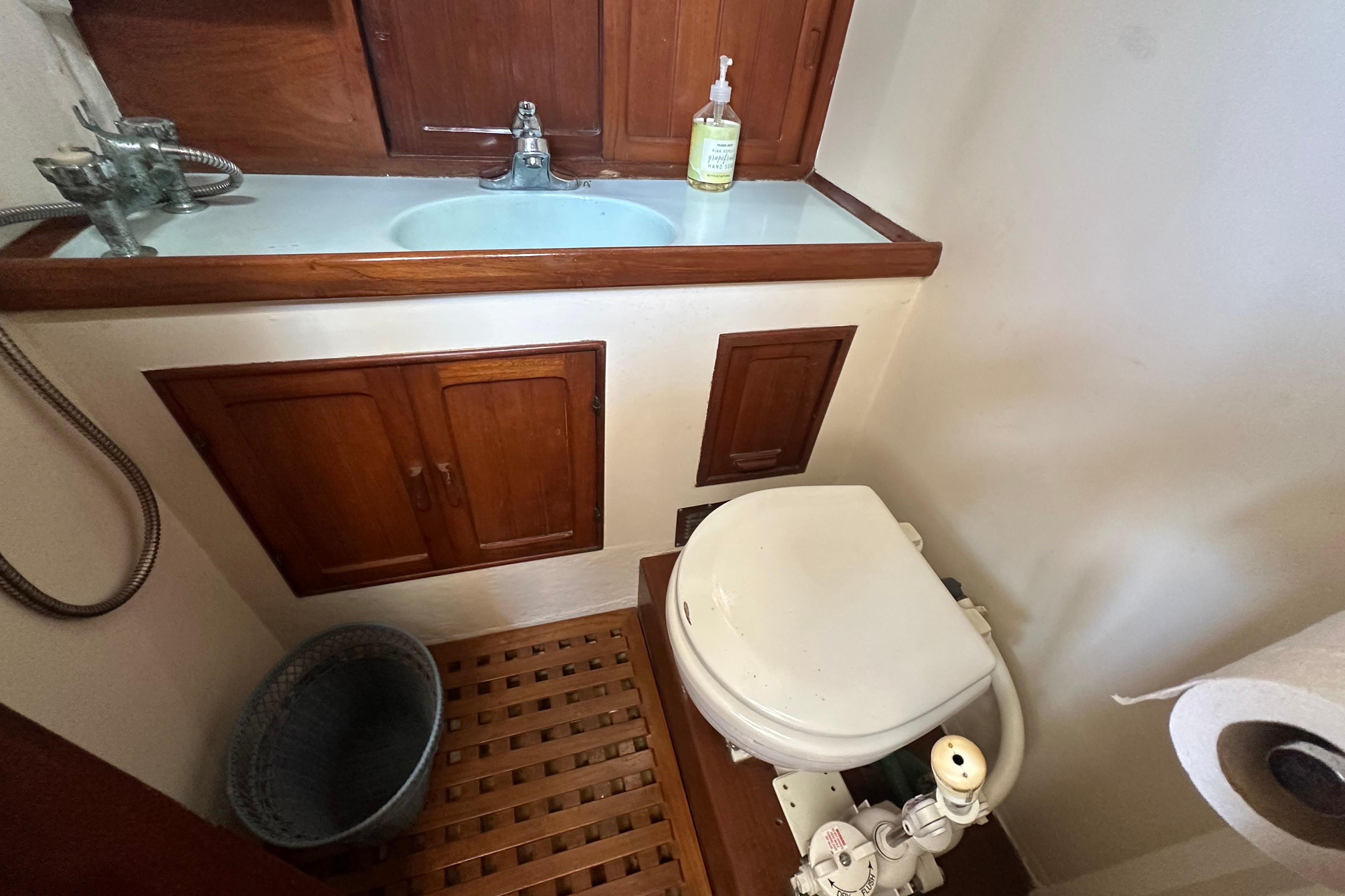 1973 CHB 33 boat bathroom with wooden cabinets, sink, and marine toilet.