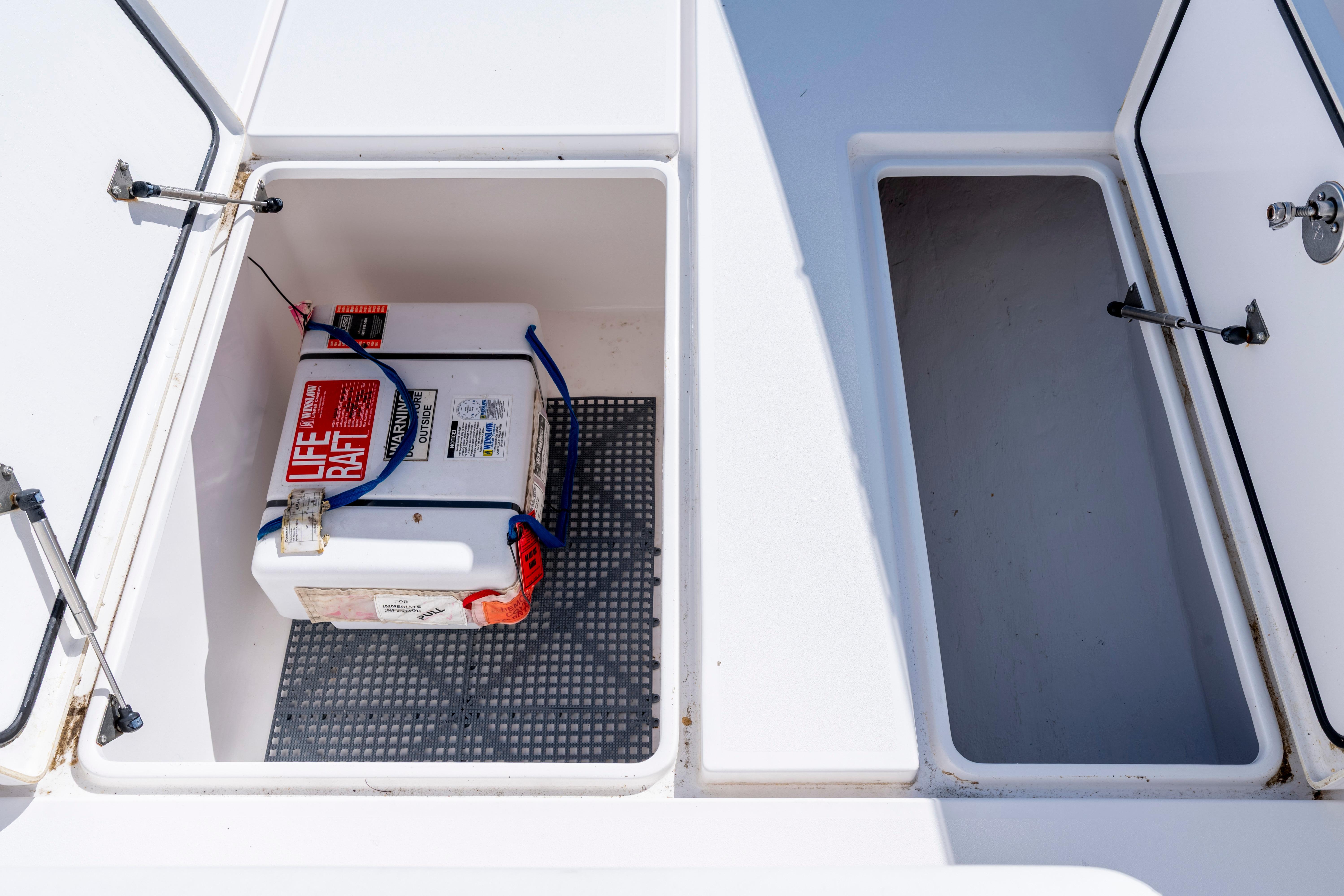Open storage compartments on a 2015 Contender 39 ST boat, featuring a secured life raft.