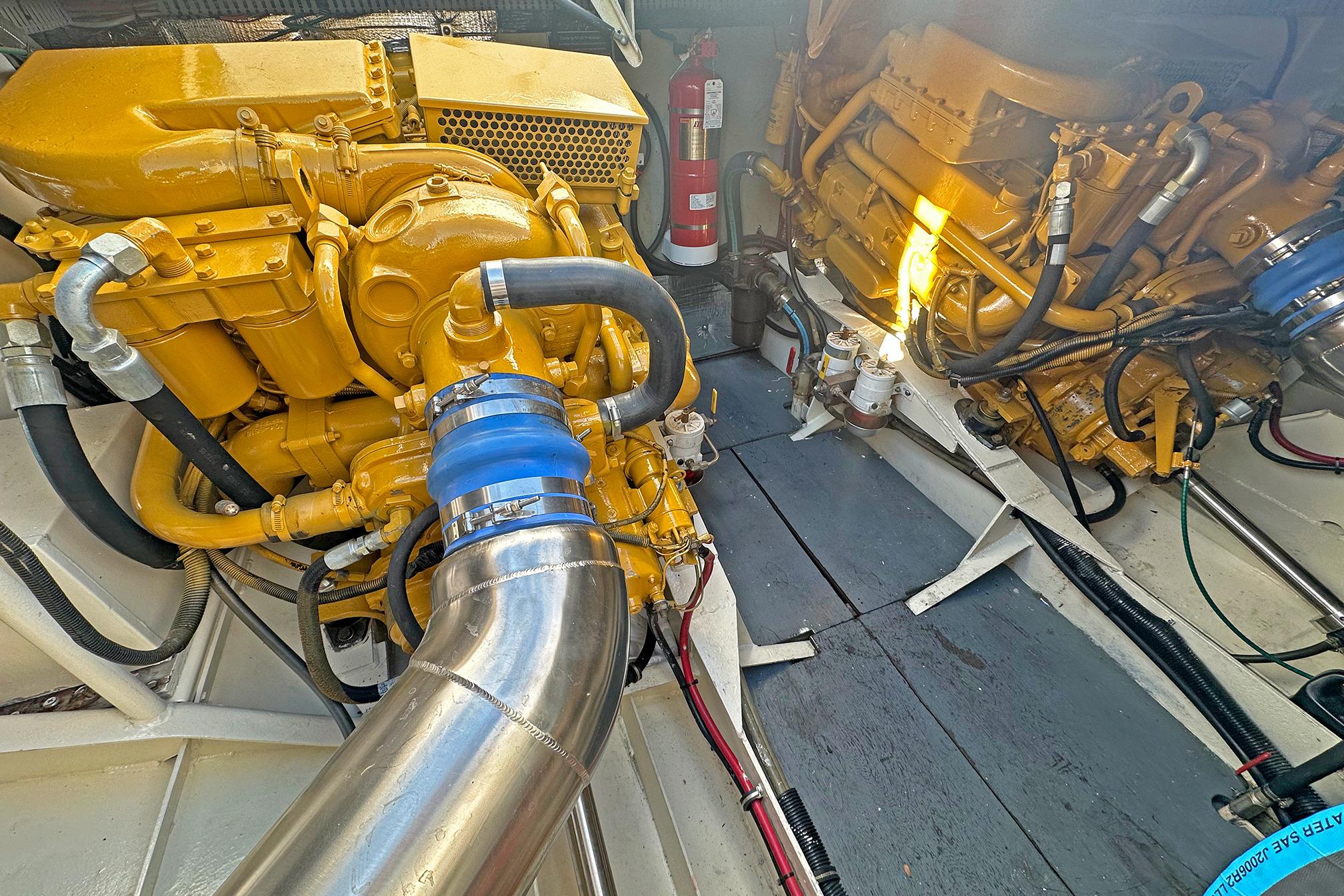 Engine room of a 1990 Boston Whaler 36 Defiance, showcasing yellow machinery and piping.