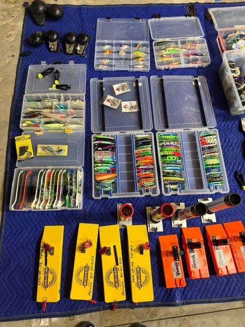 Fishing gear on a blue blanket, featuring lures and tackle boxes.