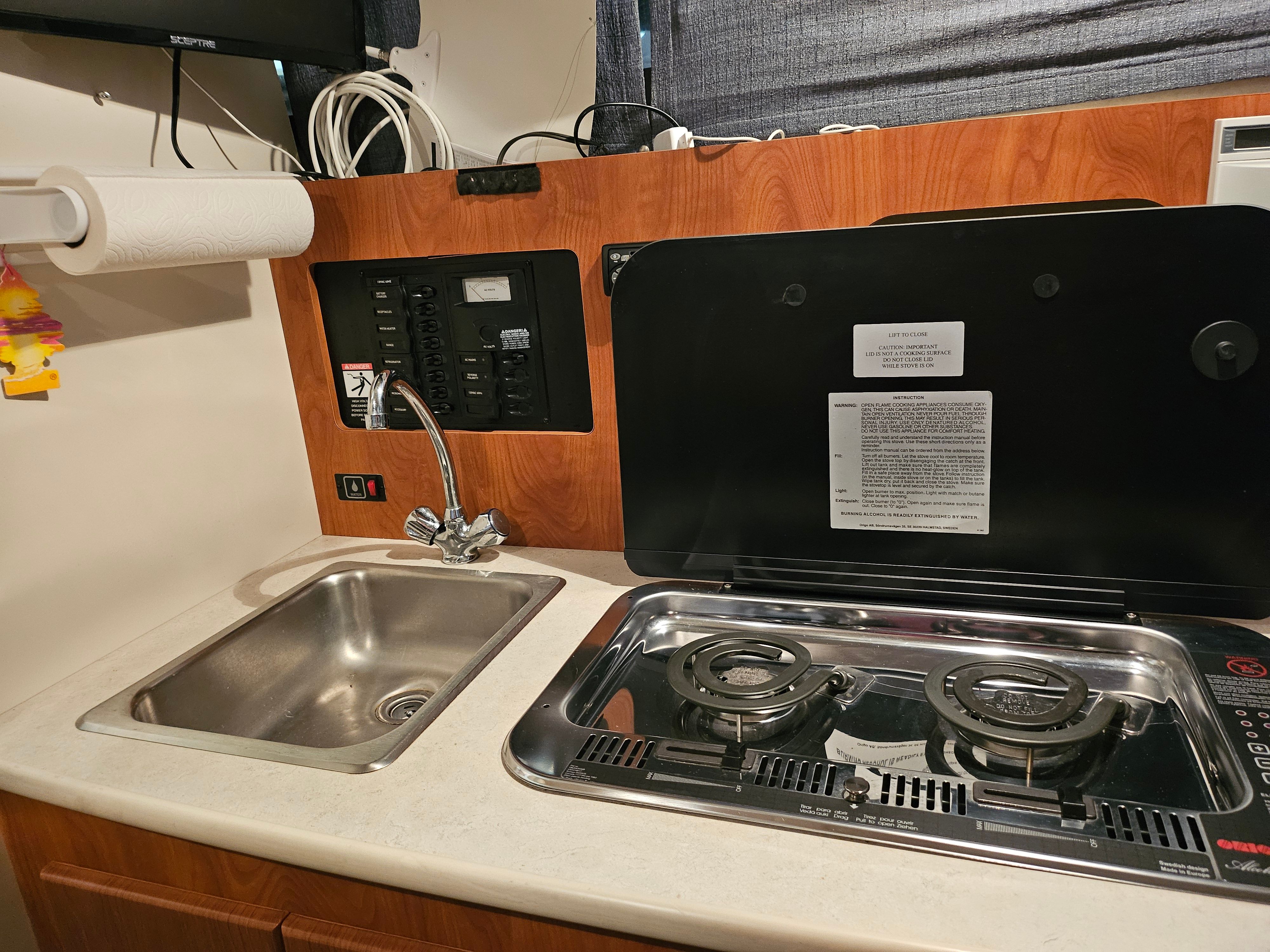 Galley area with sink and stove in a boat.