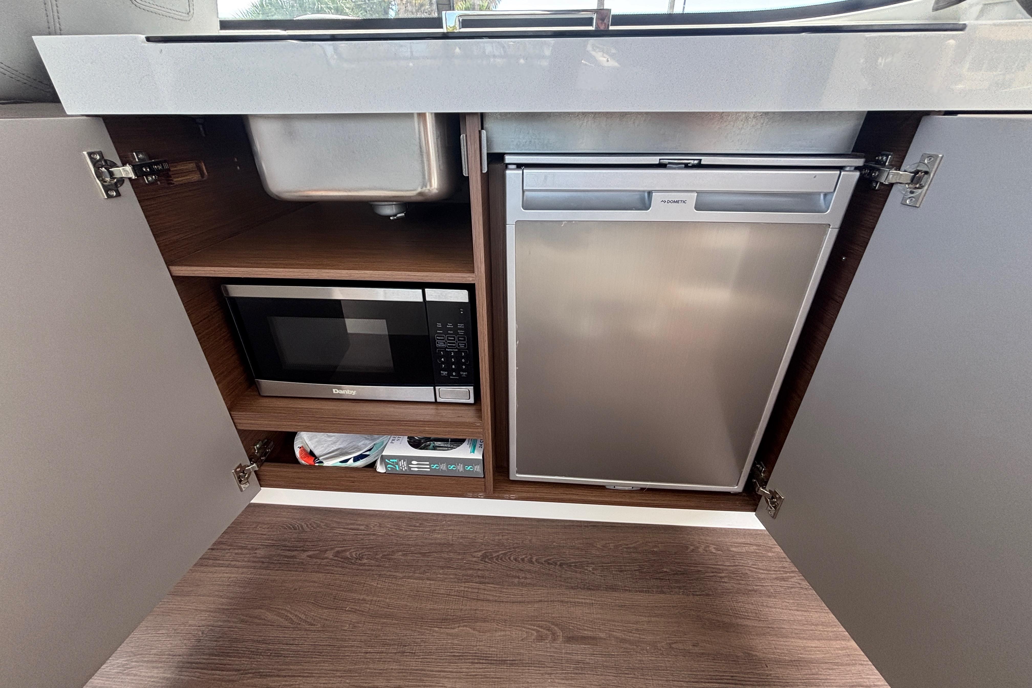 2024 Beneteau Antares 11 kitchen with microwave, fridge, and storage under sink.