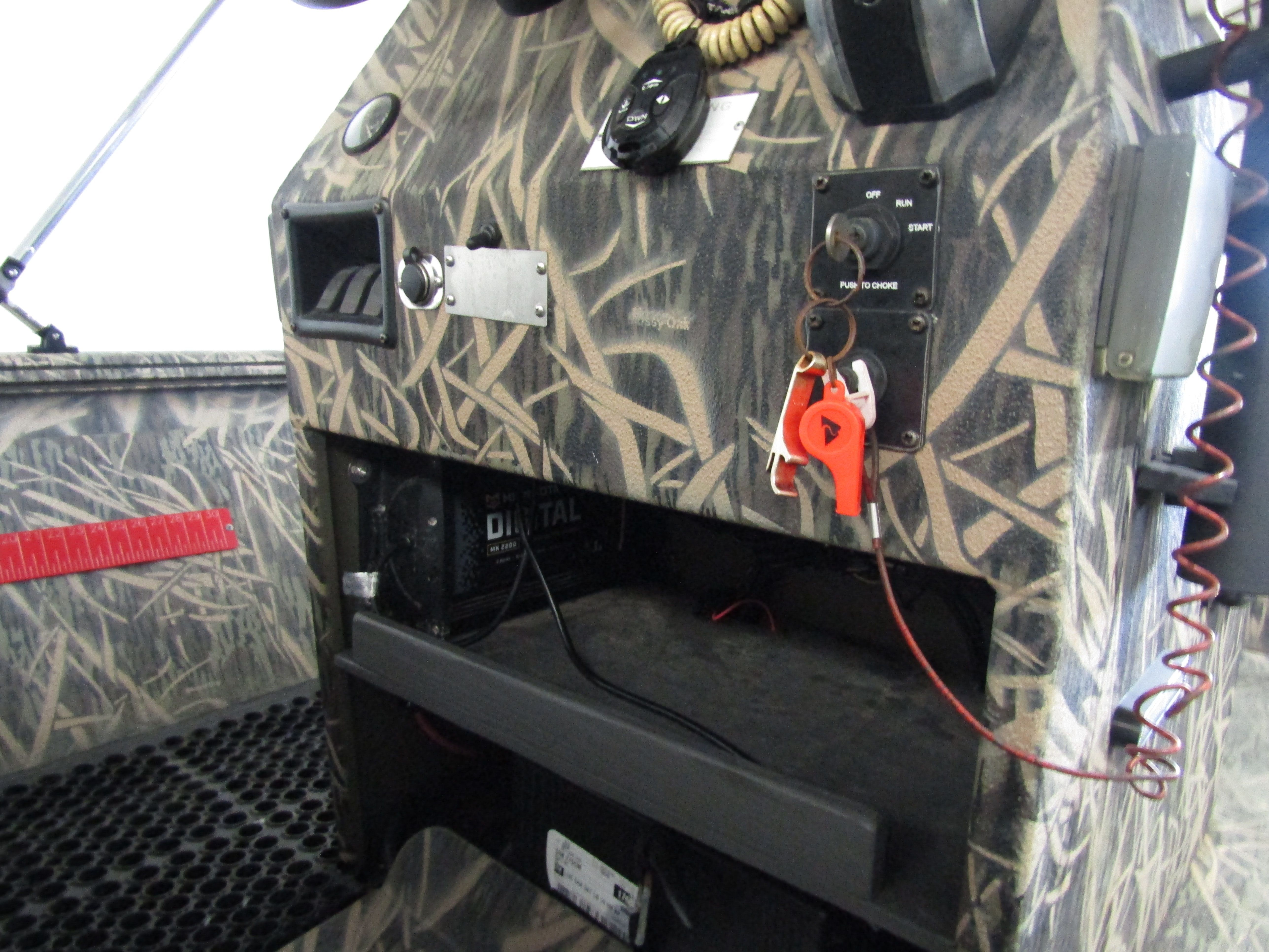 The image shows a boat dashboard with camouflage pattern and various controls.