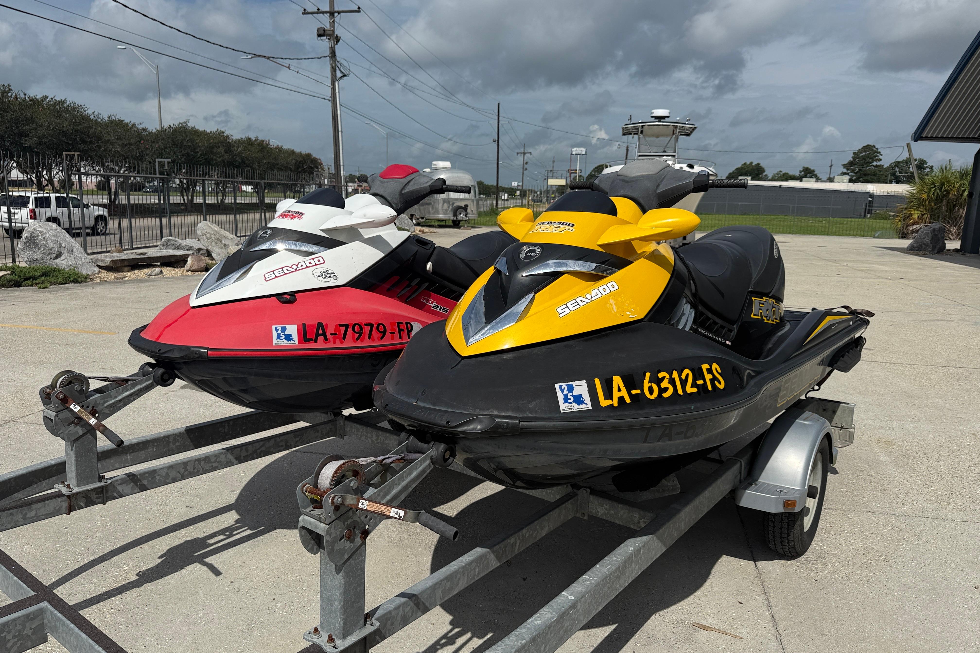 Two 2007 Sea-Doo RXT 215 jet skis on a trailer, parked outdoors.