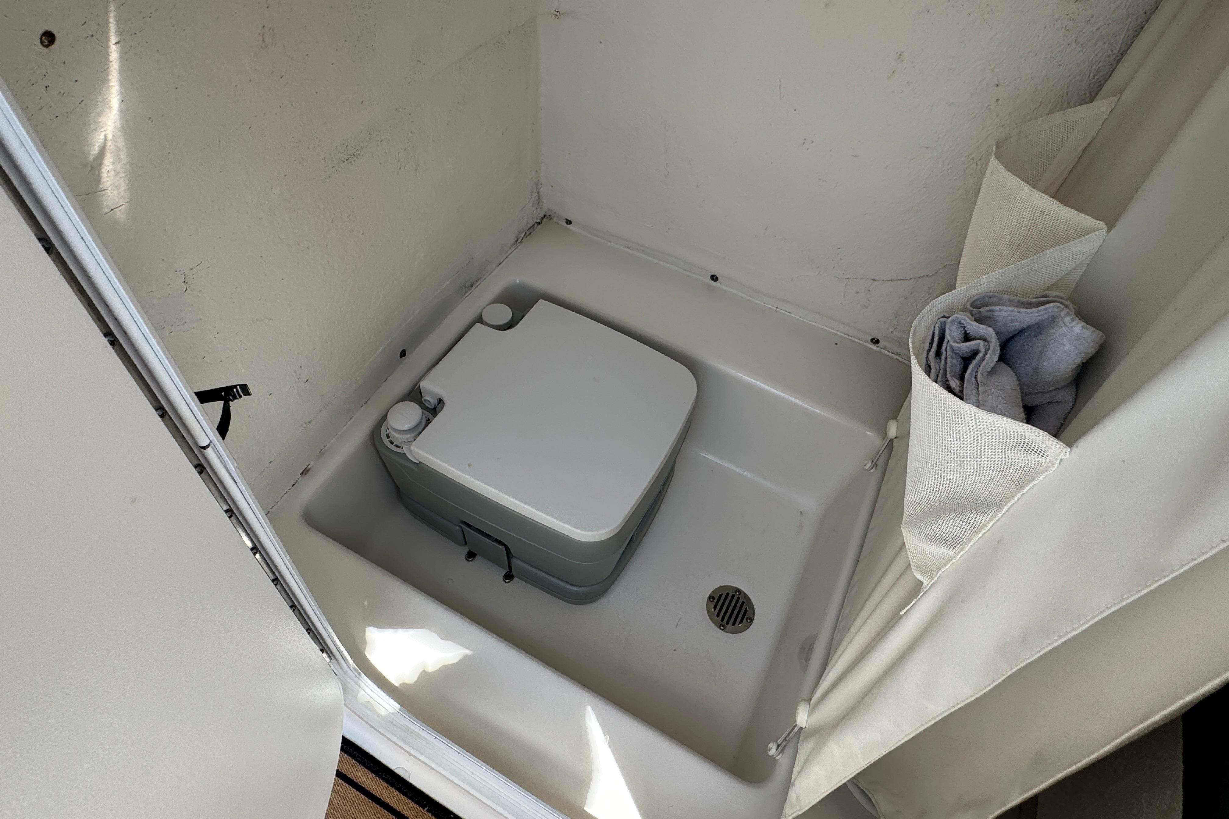 Compact bathroom area in a 2016 Tidewater 230 LXF boat with portable toilet.