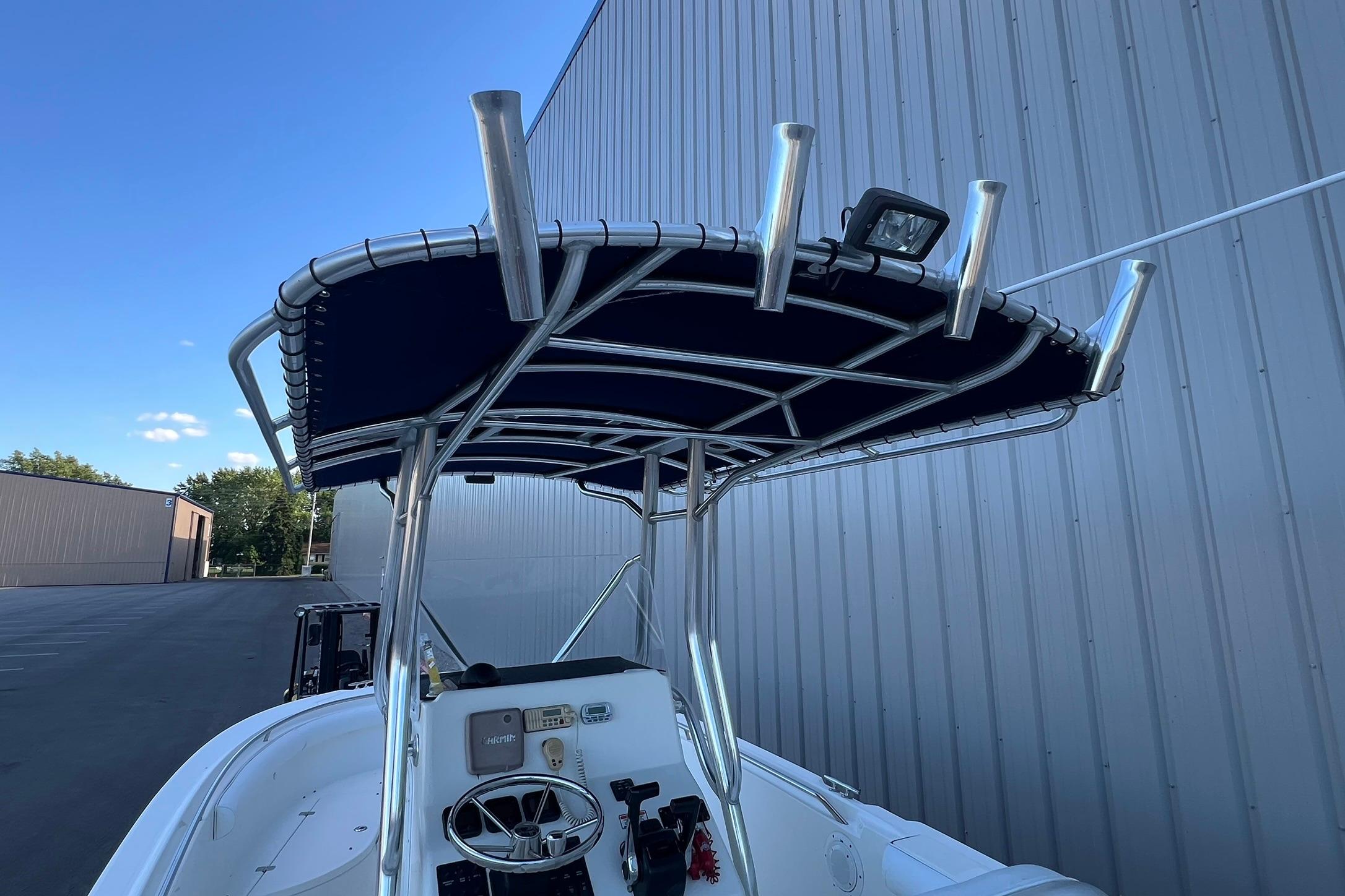 2006 Edgewater 245CC boat with T-top and steering console, parked near a metal building.